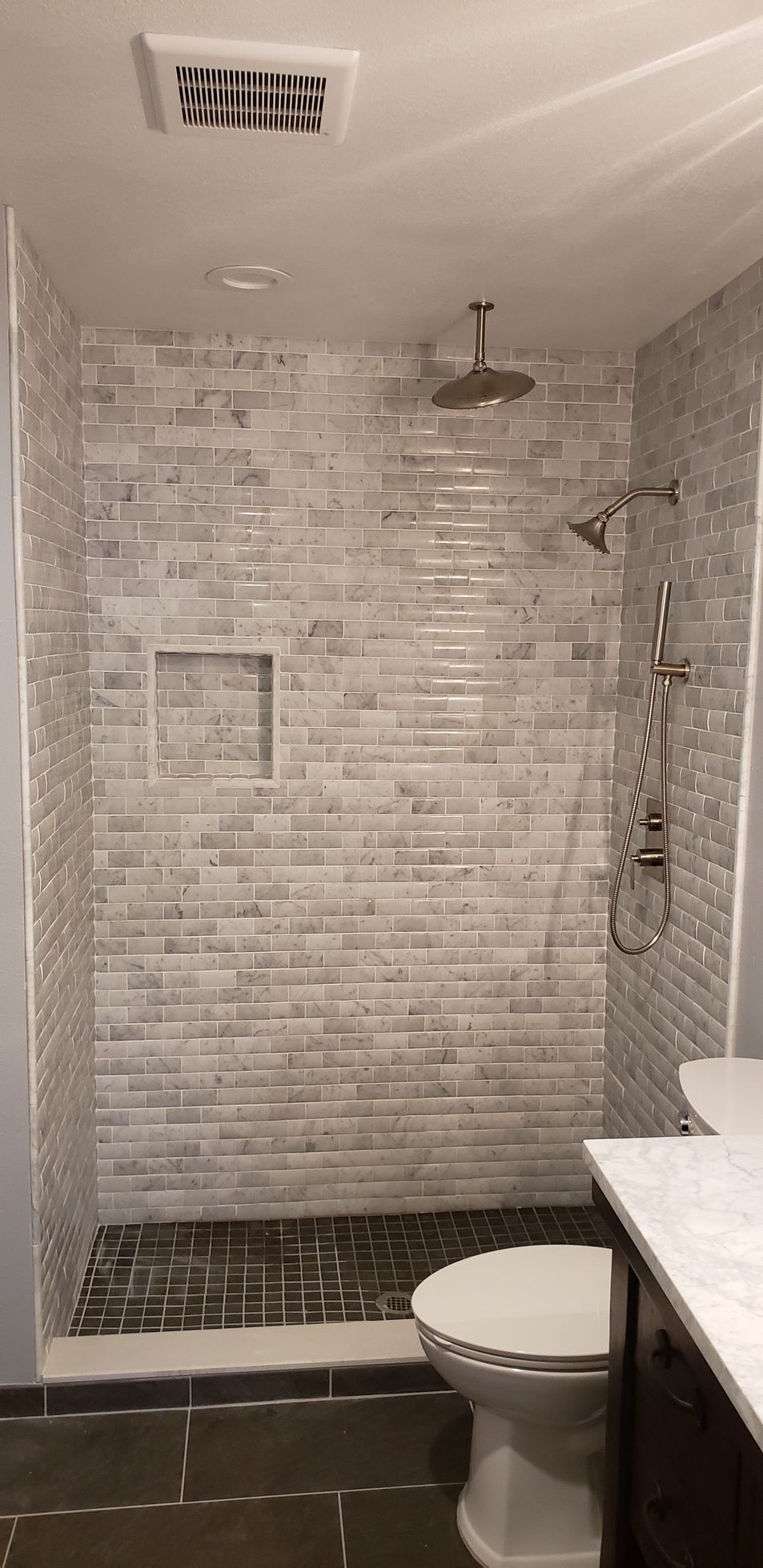 A bathroom with a toilet , shower , and ceiling fan.