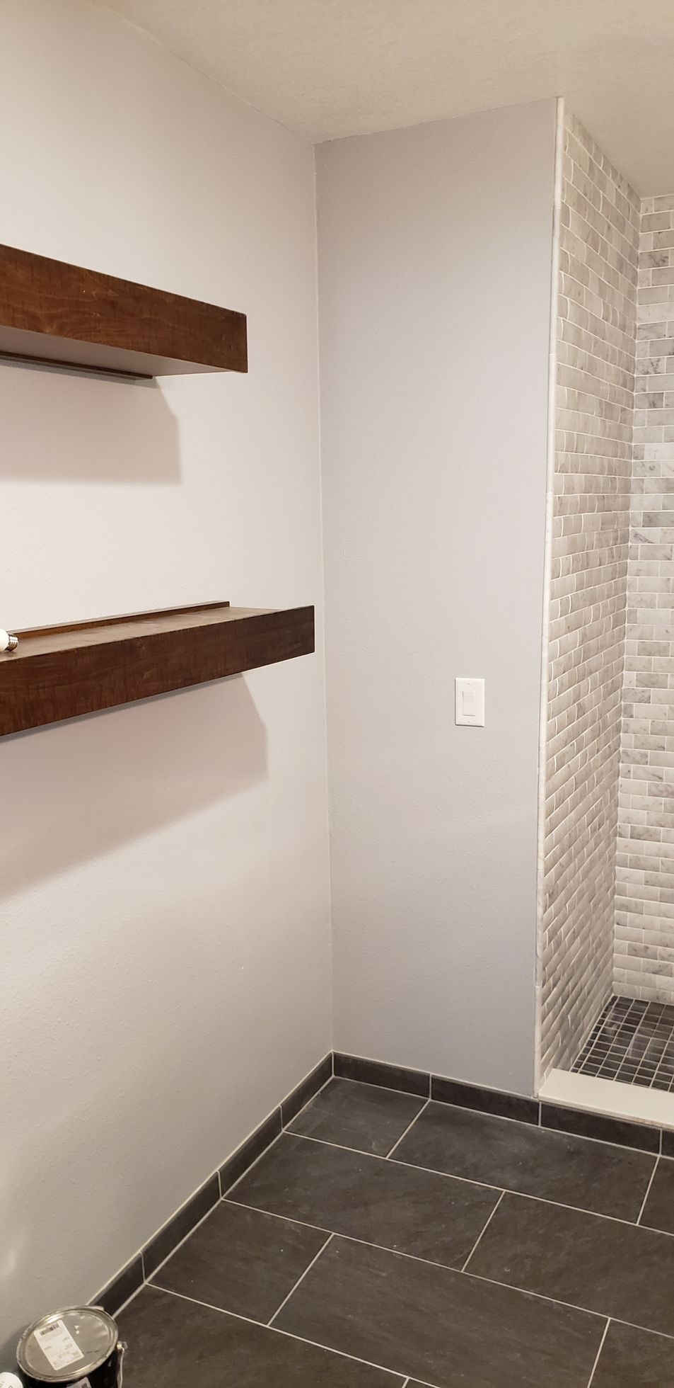 A bathroom with two shelves and a walk in shower.