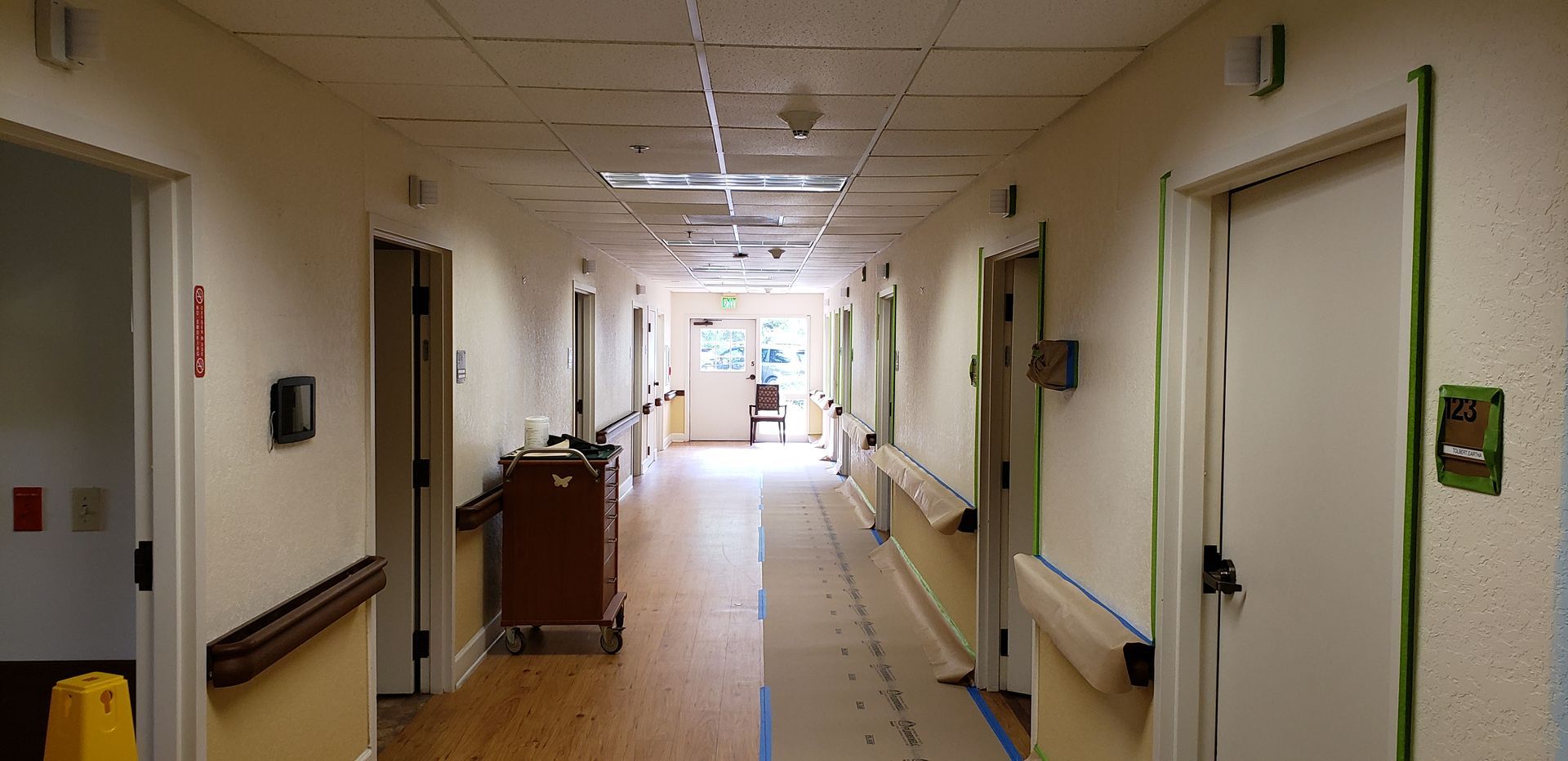 A long hallway in a hospital with a yellow safety mat on the floor.