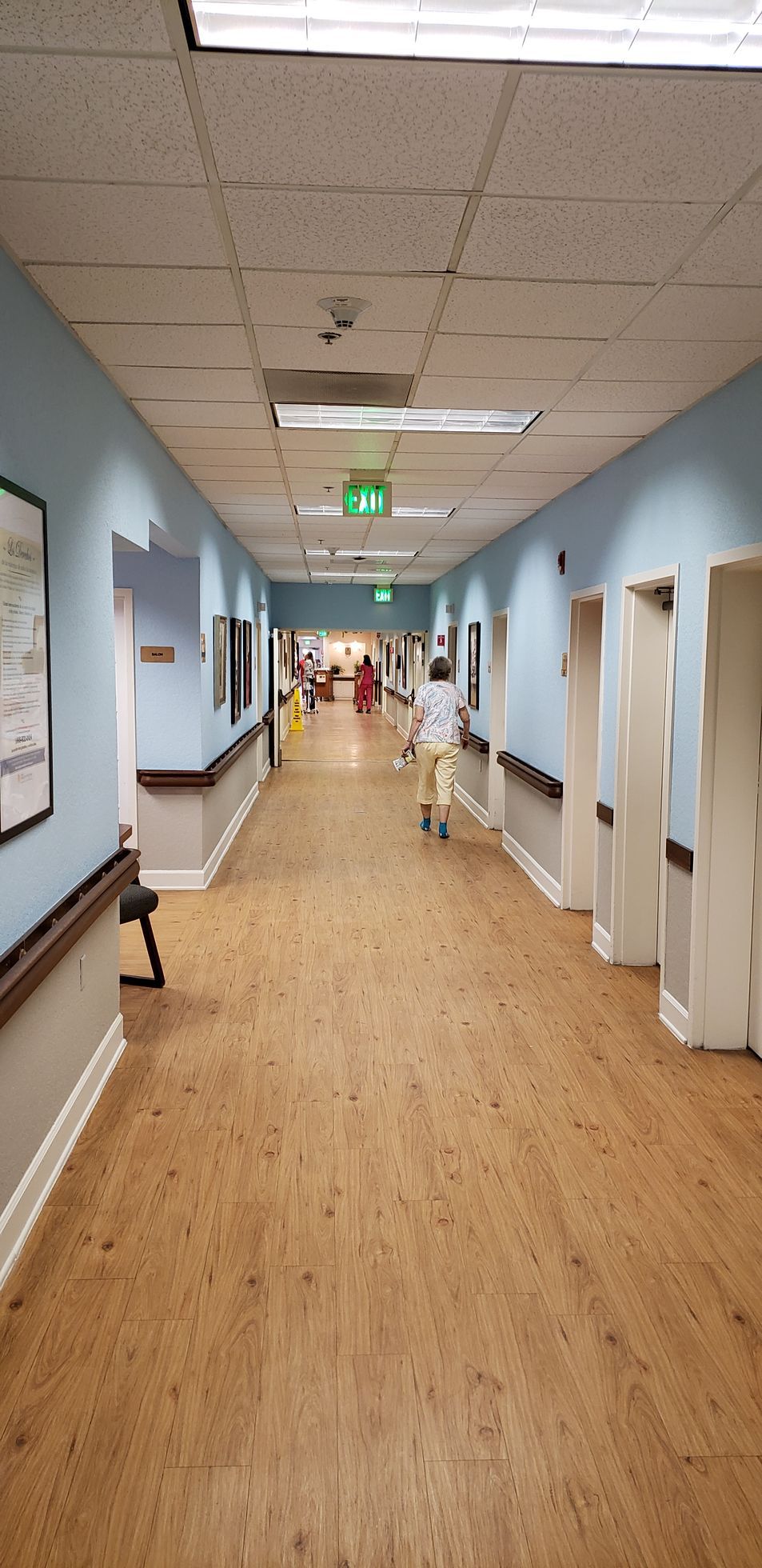 A long hallway in a hospital with people walking down it.