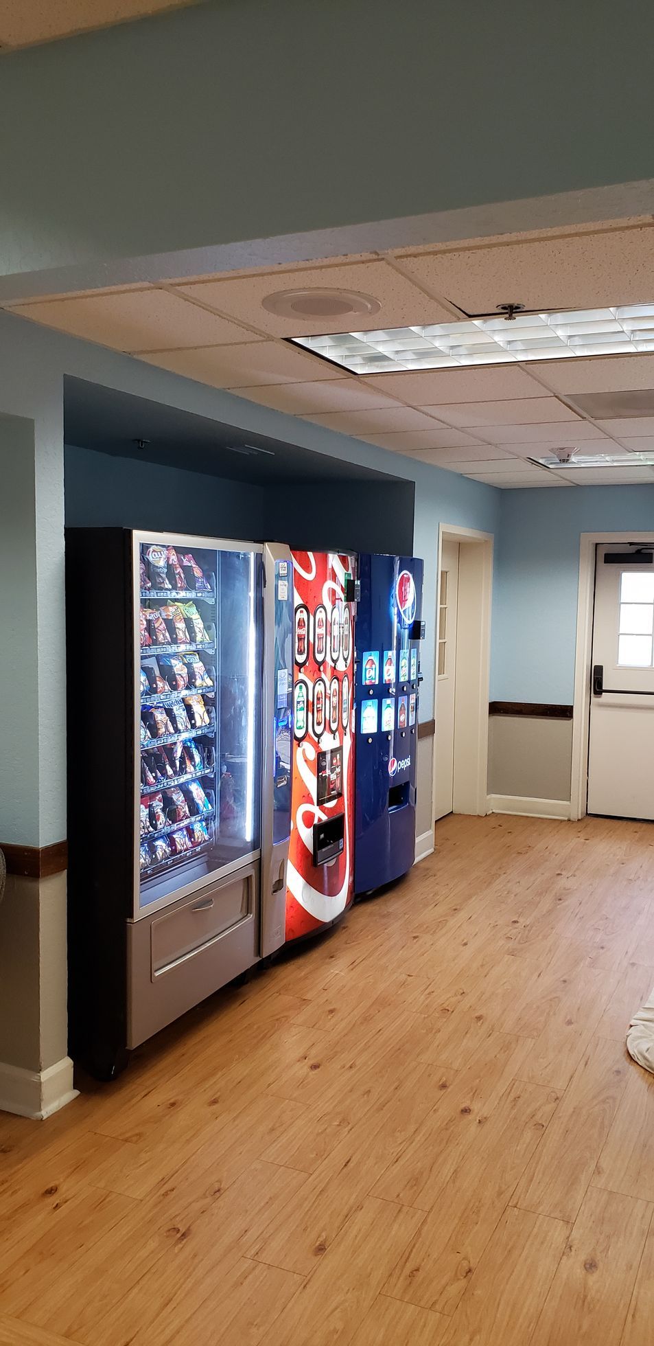A hallway filled with vending machines and a door.