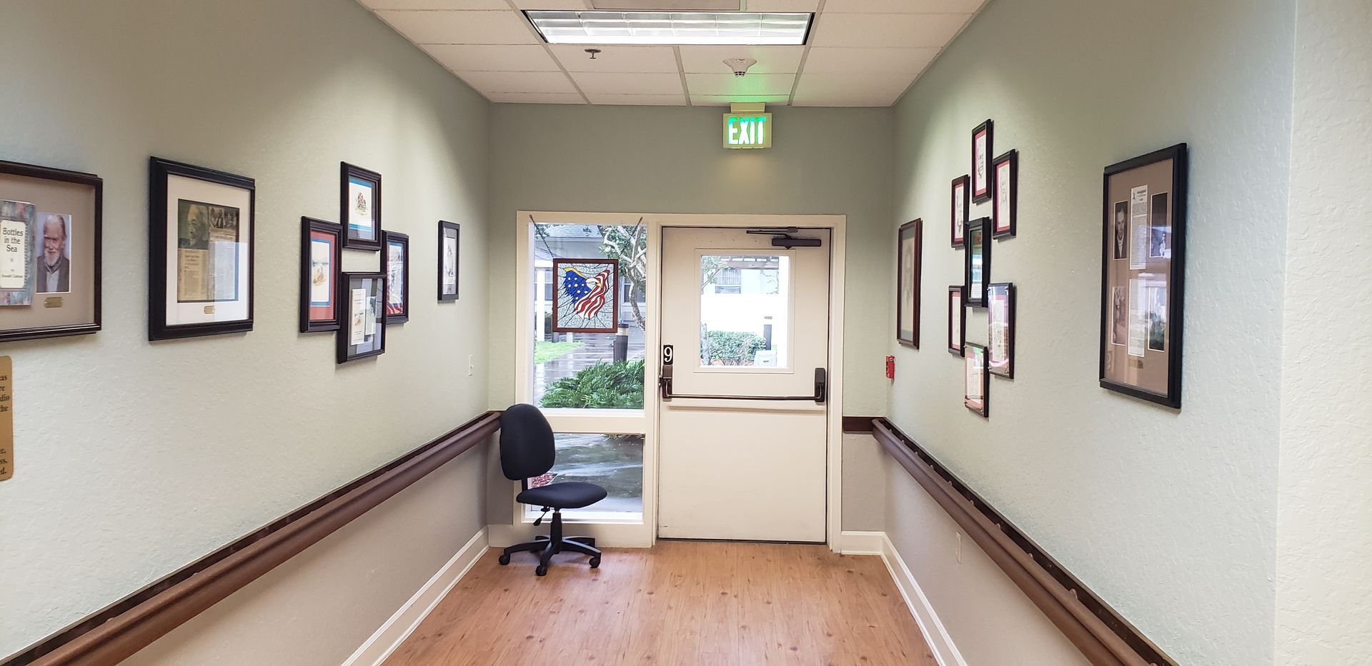 A long hallway with pictures on the wall and a chair