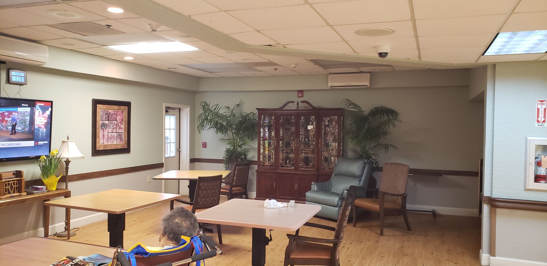 A large room with tables and chairs in a nursing home.