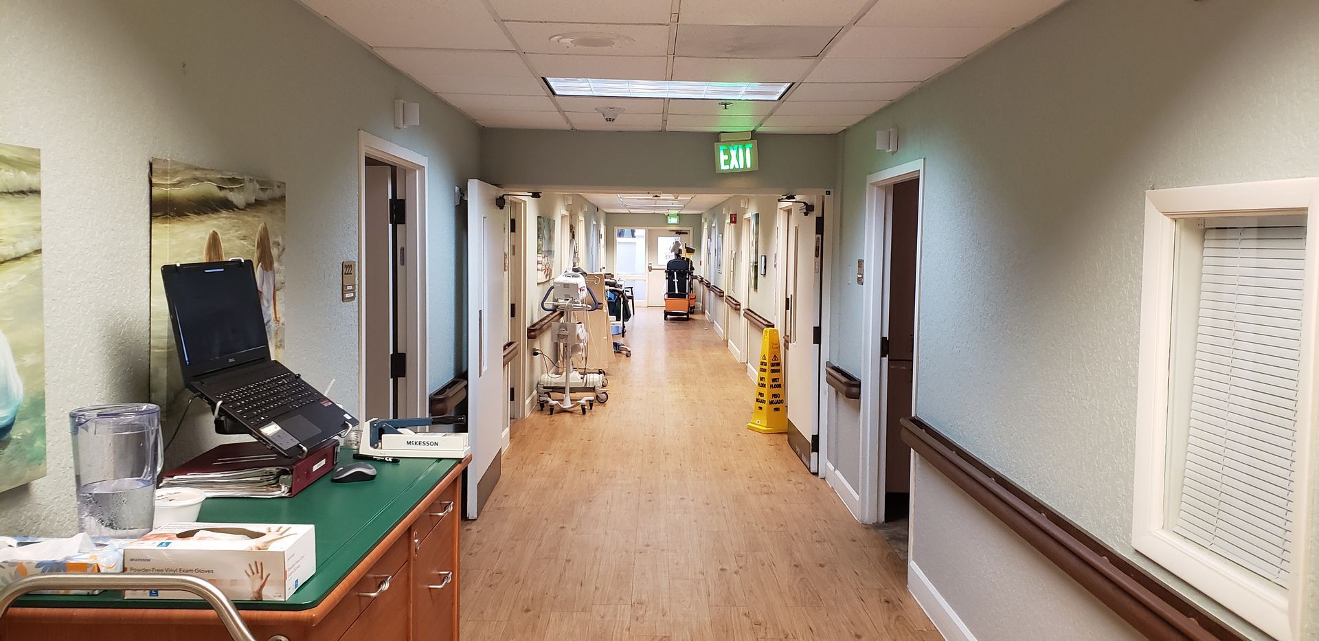 A long hallway in a hospital with a yellow mop on the floor.
