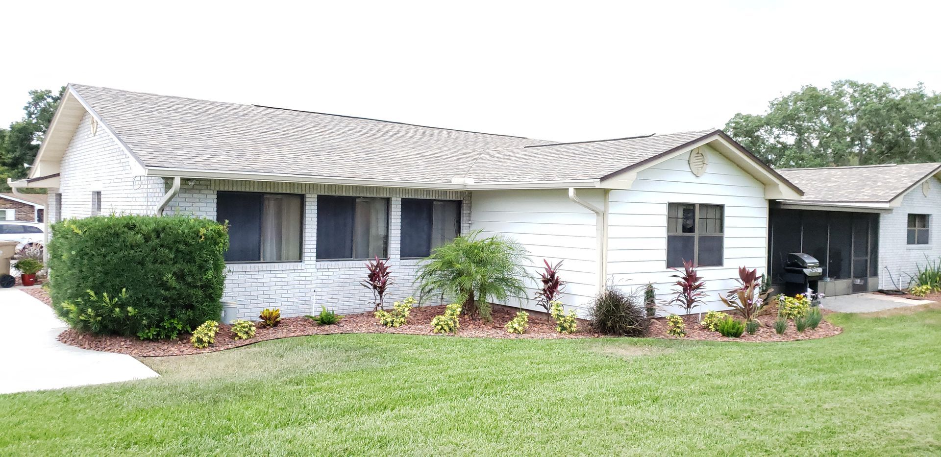 A white house with a gray roof is sitting on top of a lush green lawn.