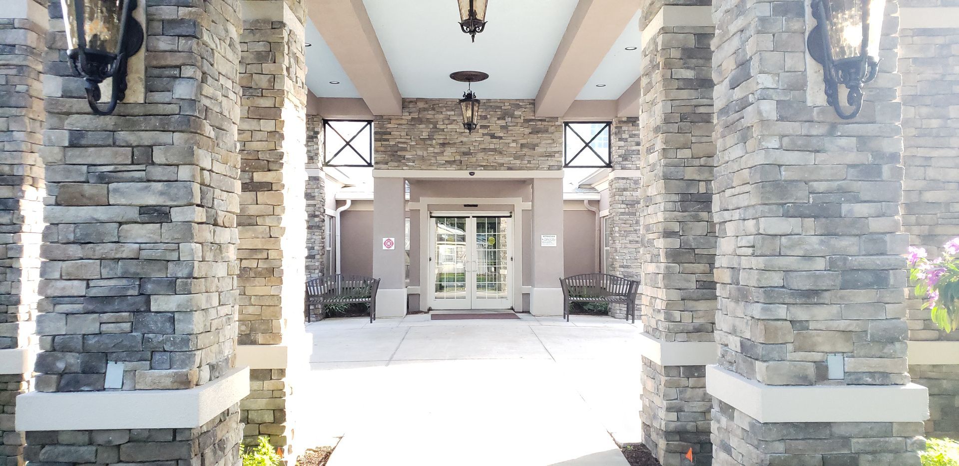 The entrance to a building with a stone wall and pillars