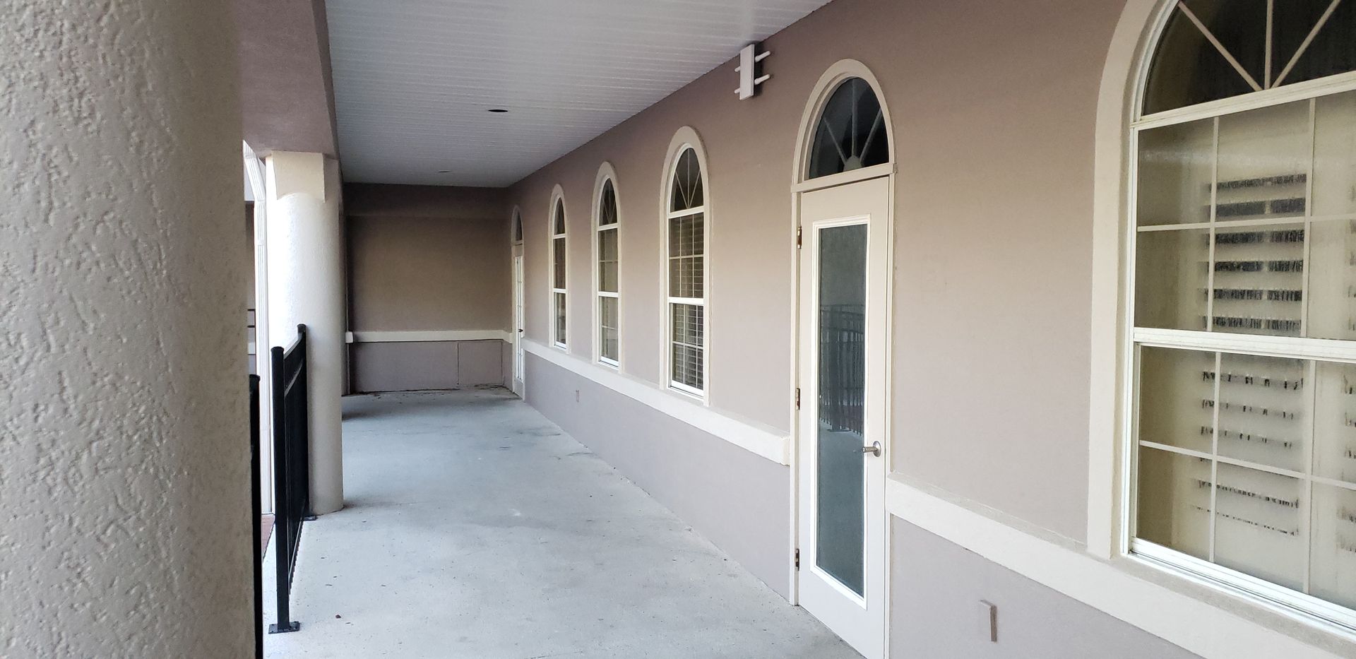 A long hallway with arched windows and a door
