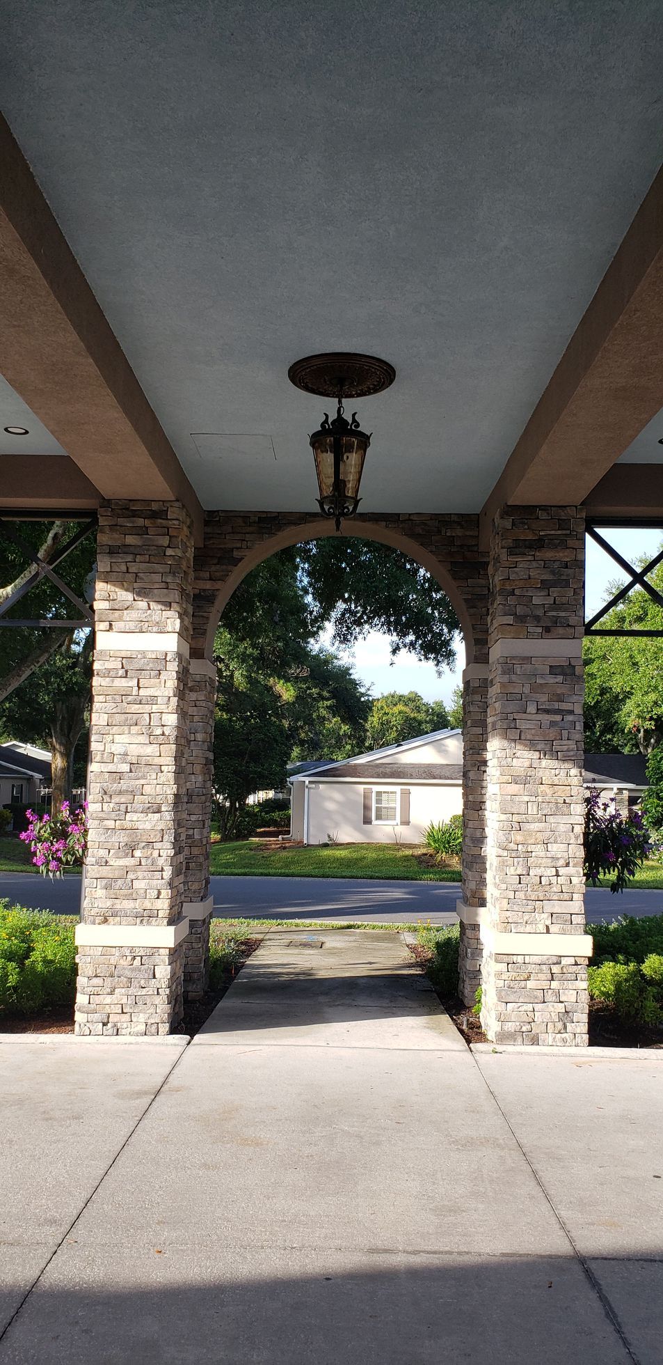 A stone archway leading to a house with a lantern hanging from the ceiling.