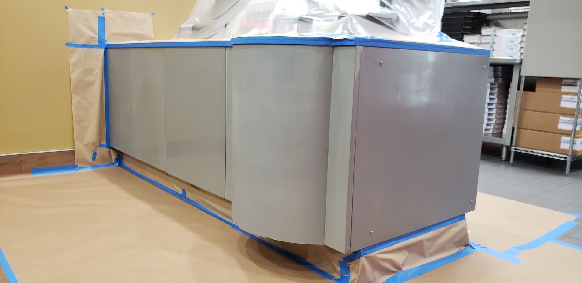 A counter is being painted in a room with blue tape.