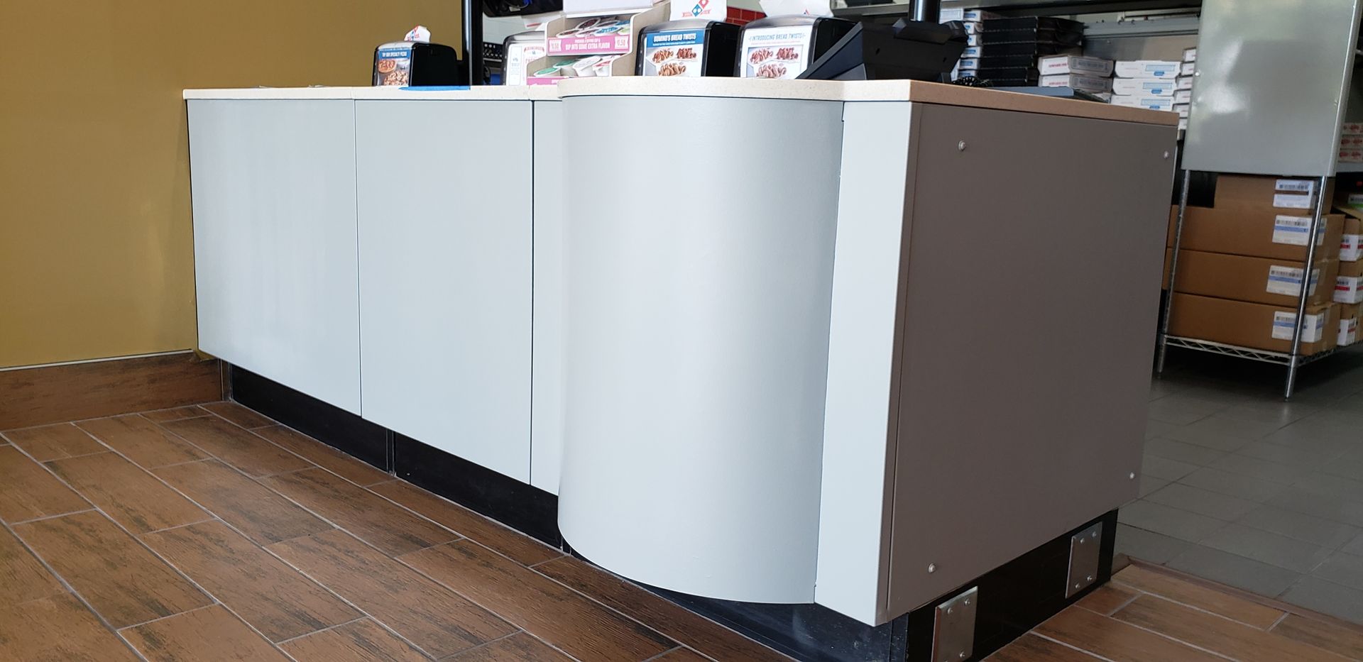 A long white counter is sitting on a wooden floor in a room.