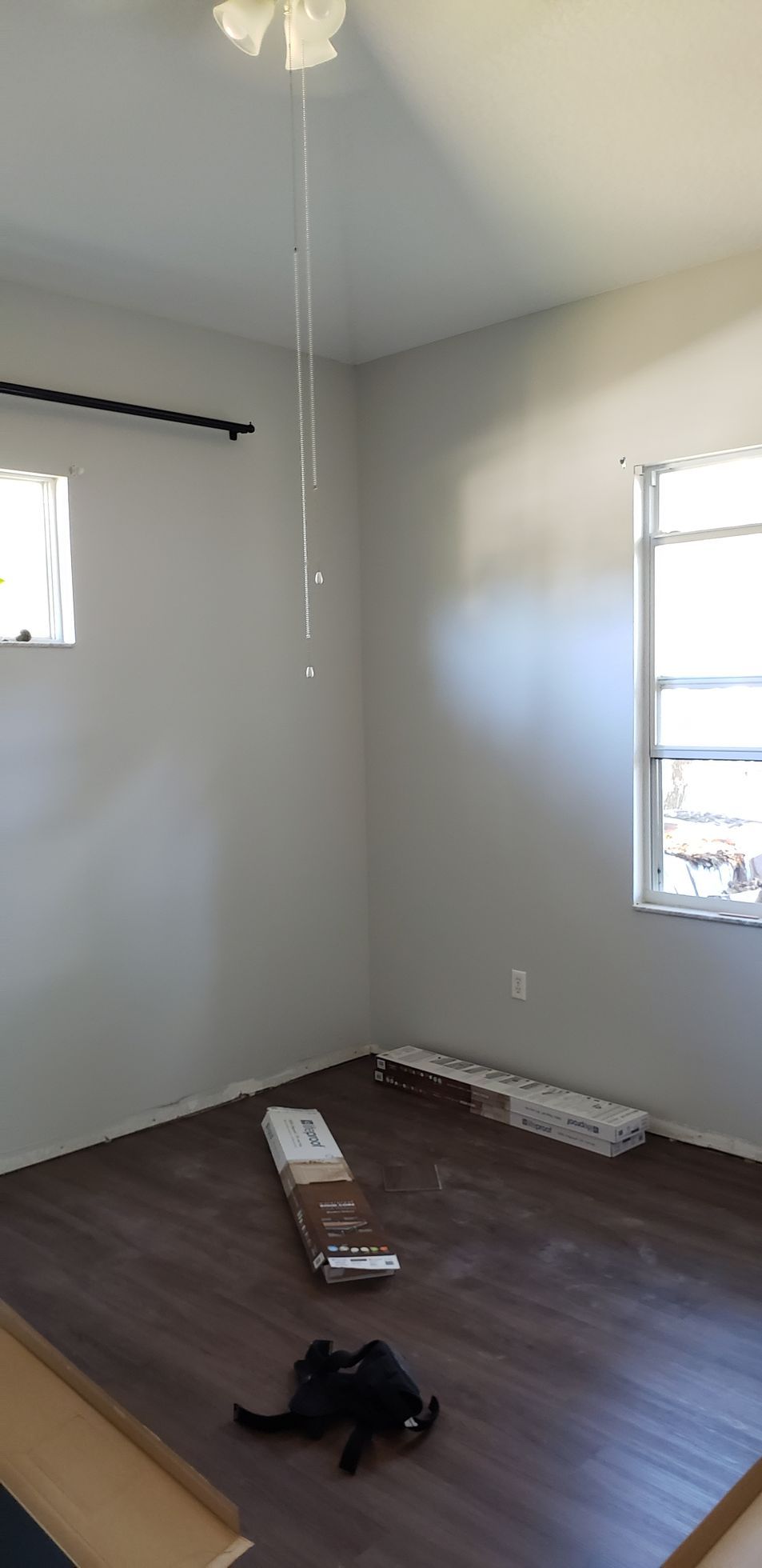 An empty room with a ceiling fan and a window.