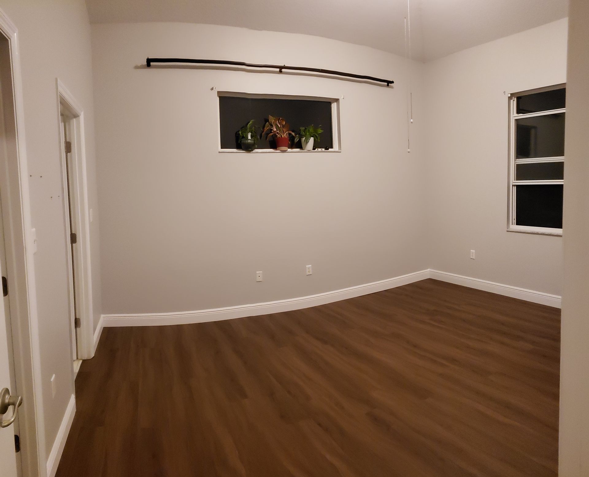An empty room with a window and a wooden floor