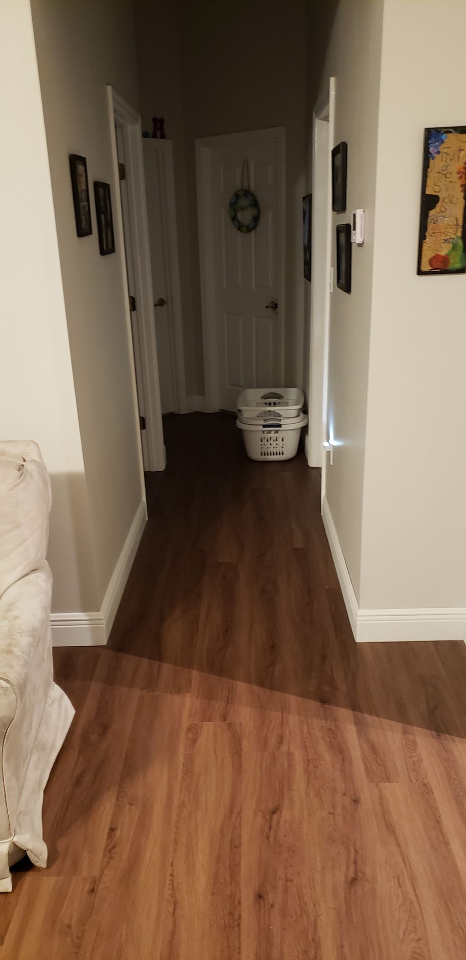A hallway in a house with hardwood floors and a laundry basket.