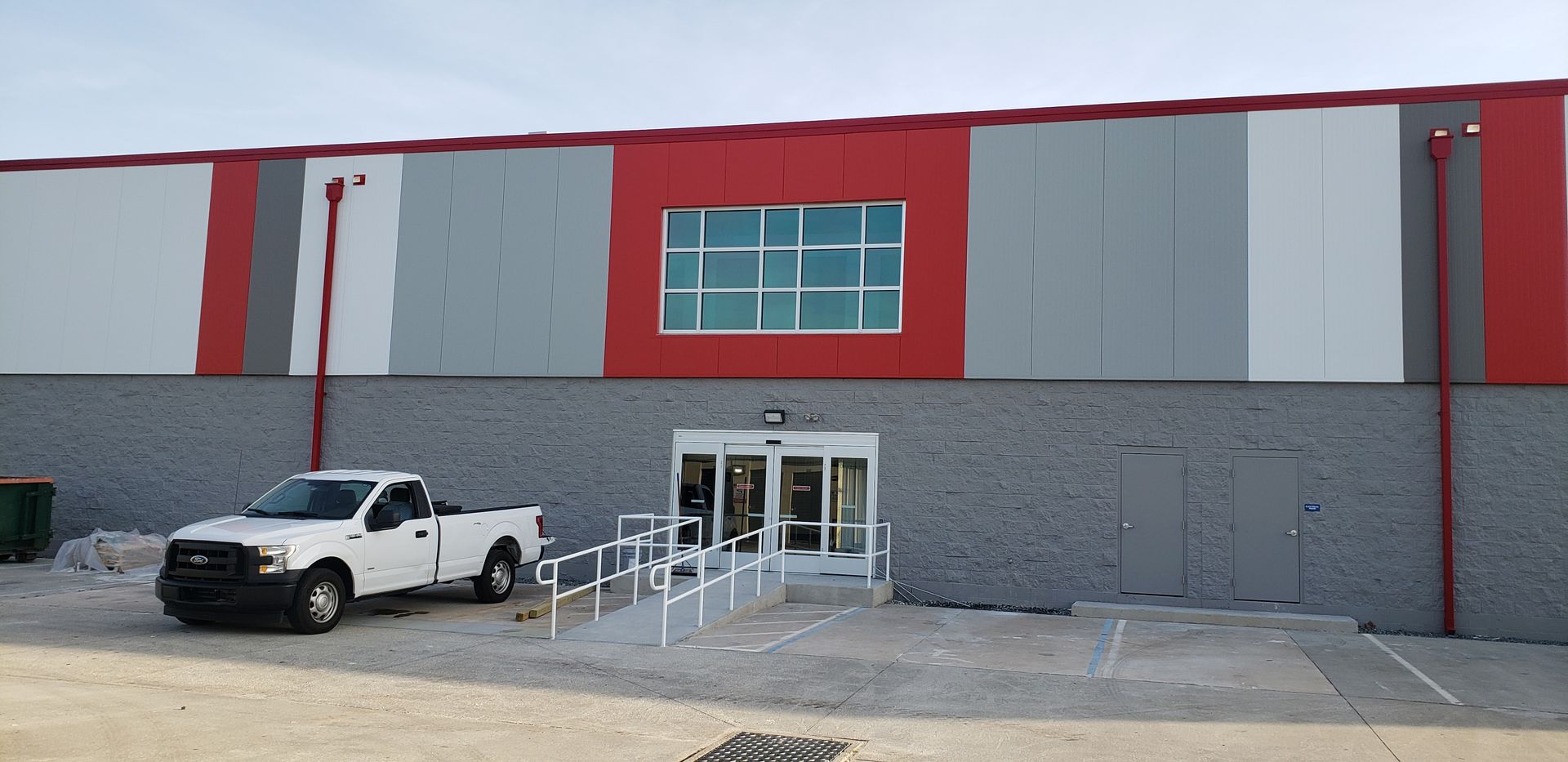 A white truck is parked in front of a large building