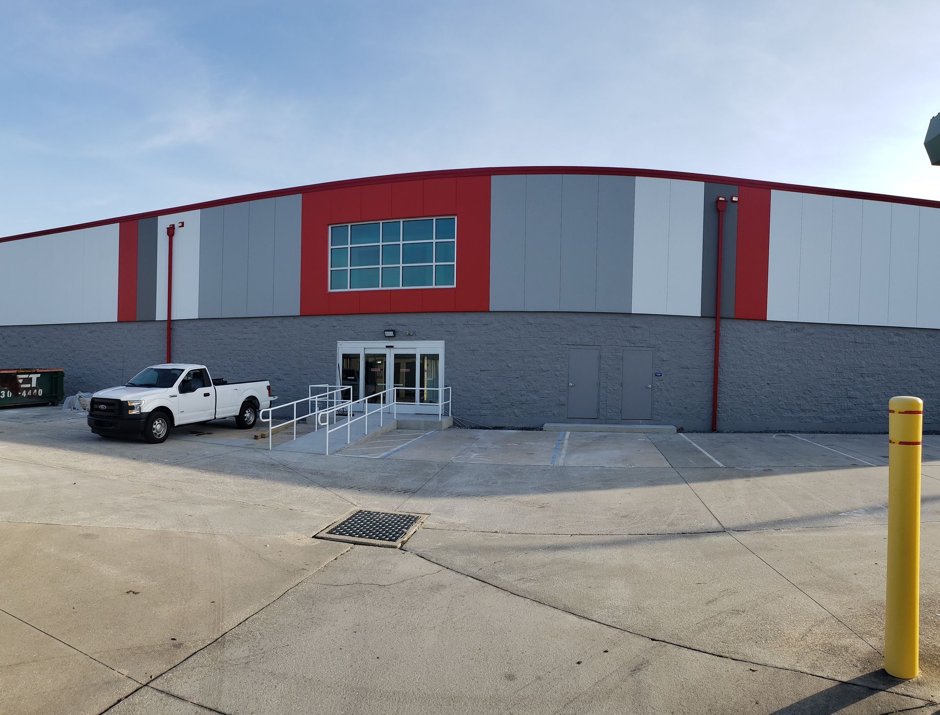 A white truck is parked in front of a large building.