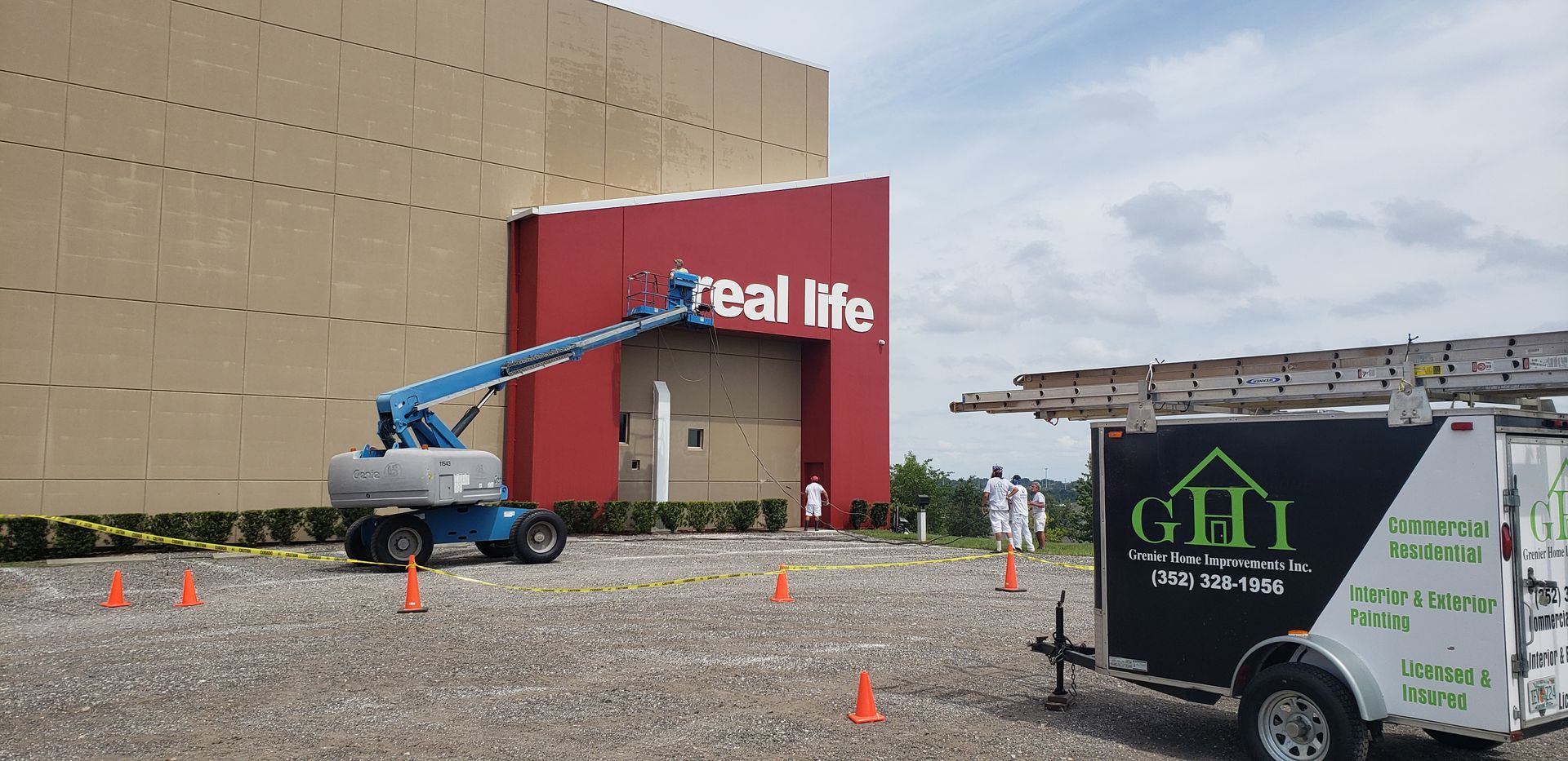 A trailer is parked in front of a building that says real life.