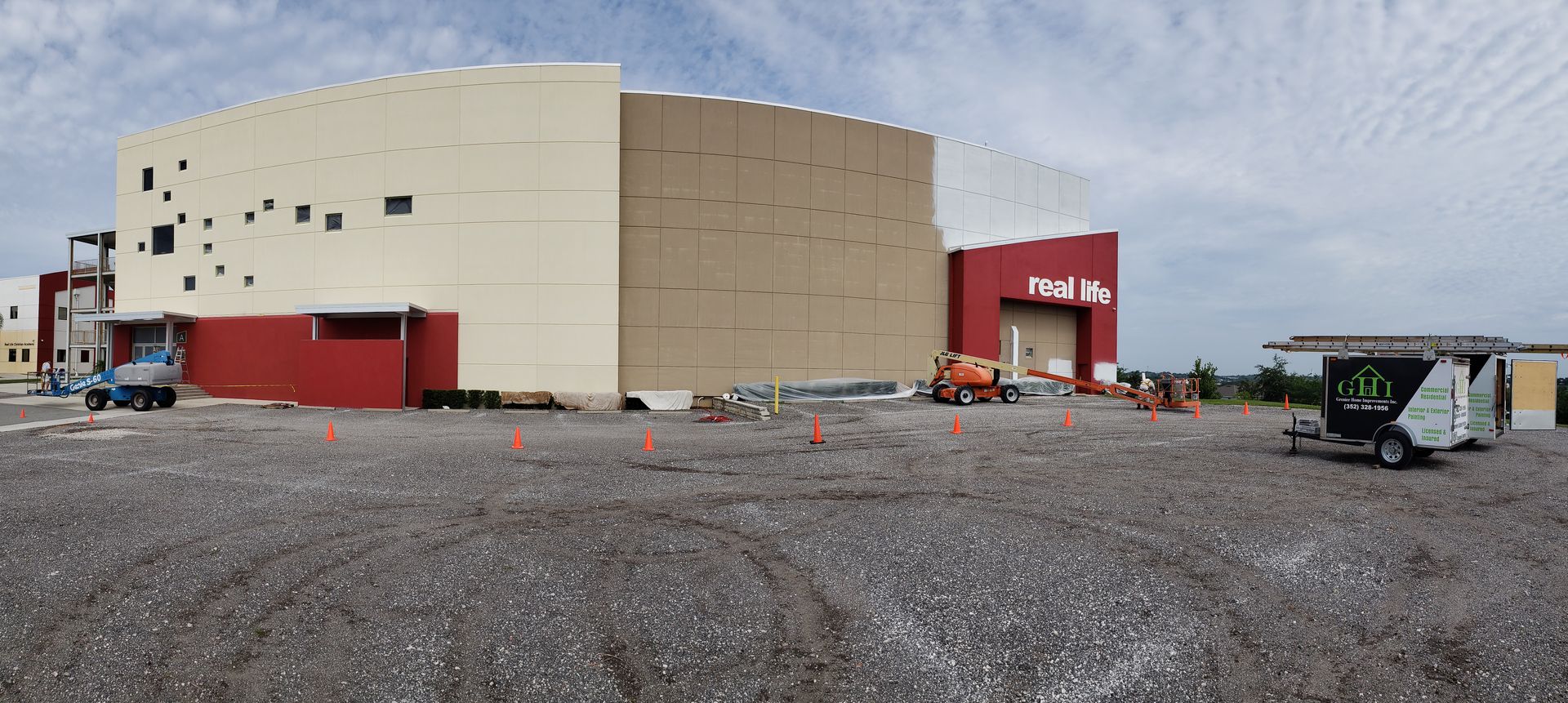 A large building is being built in a gravel lot.