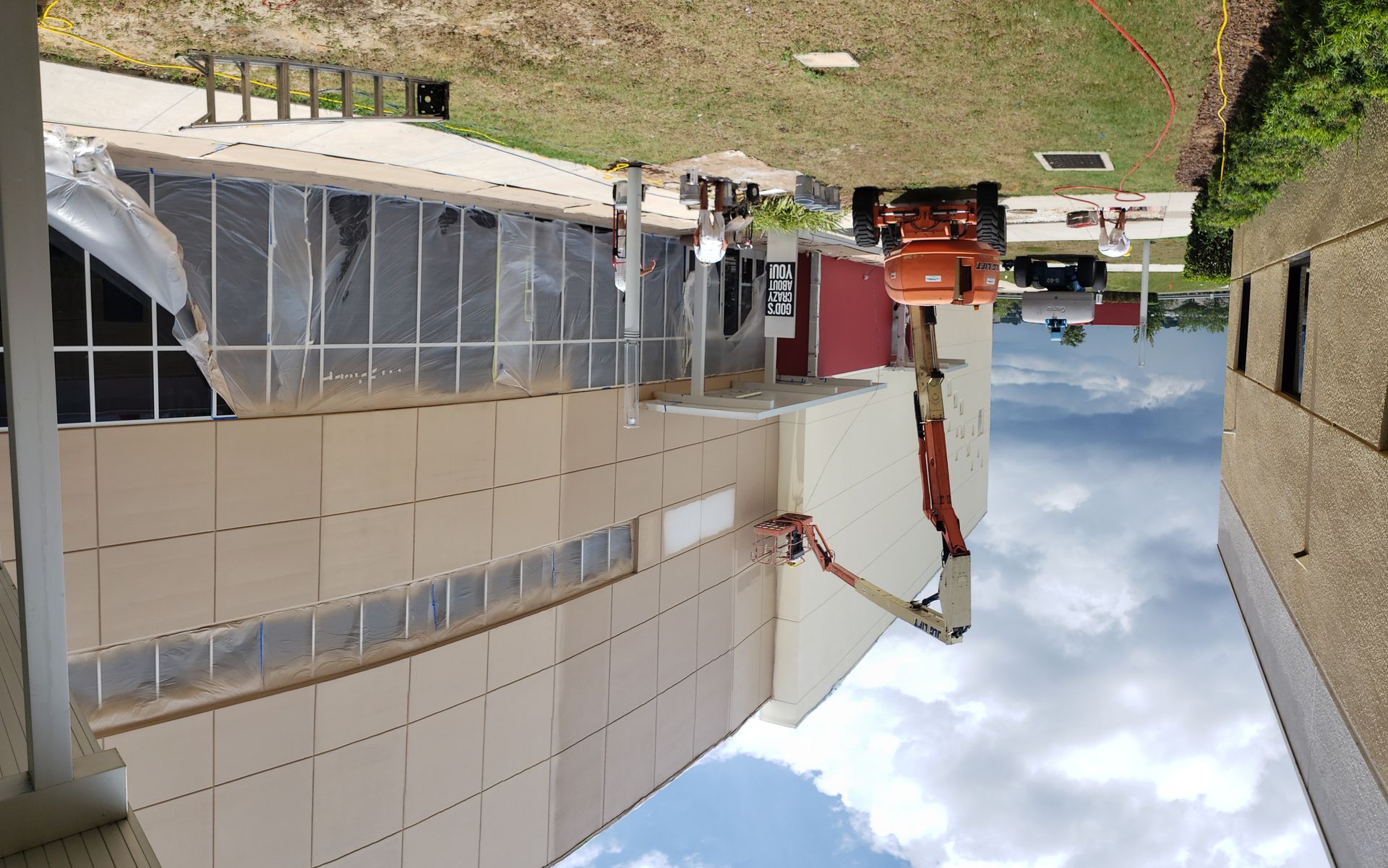 A man is standing on a lift in front of a building under construction.