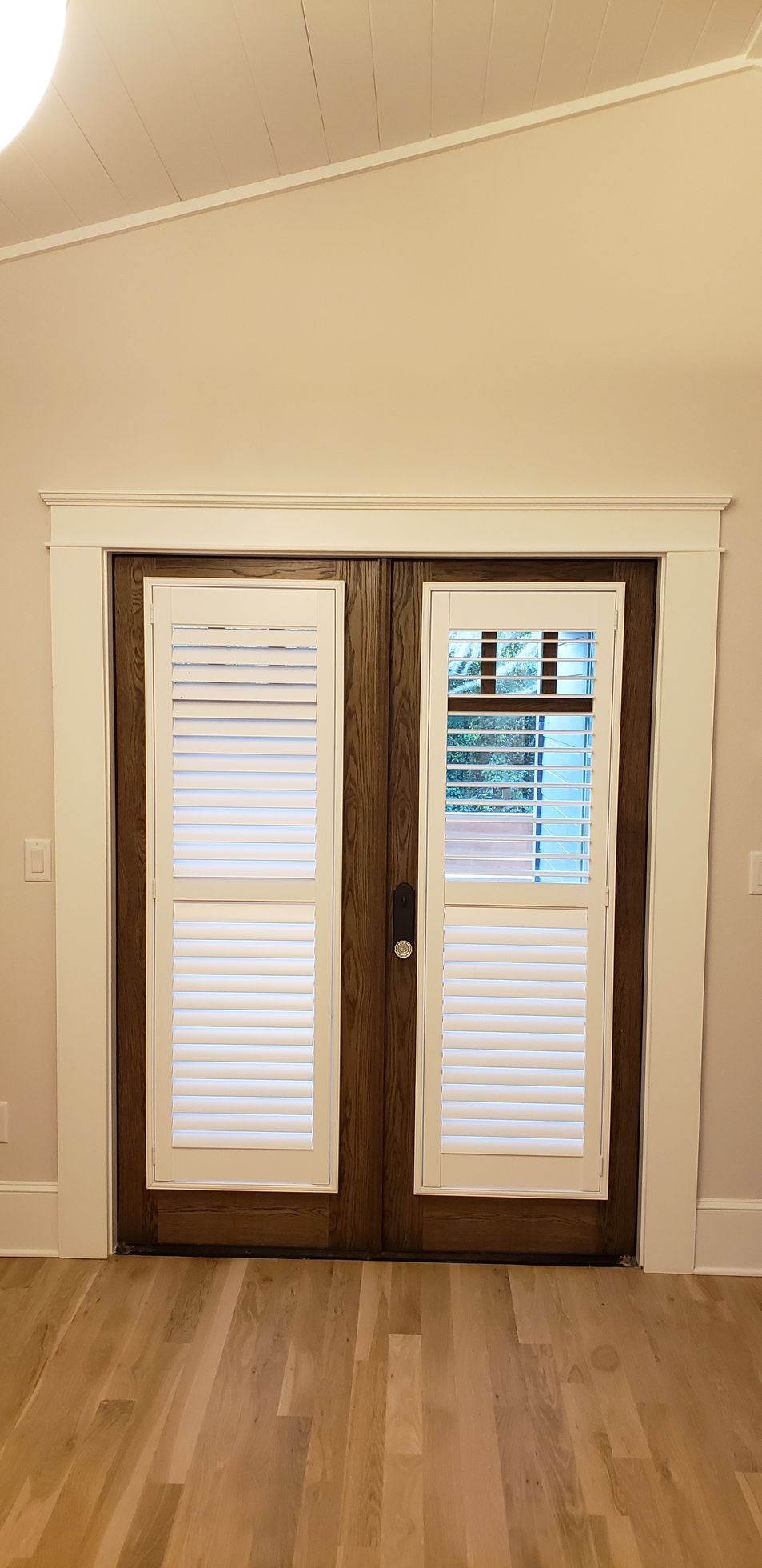 A pair of sliding glass doors with white shutters in an empty room.