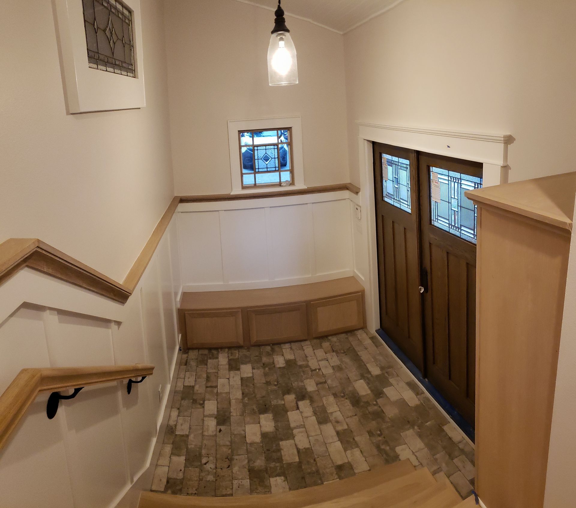 A hallway with stairs leading up to a door and a window