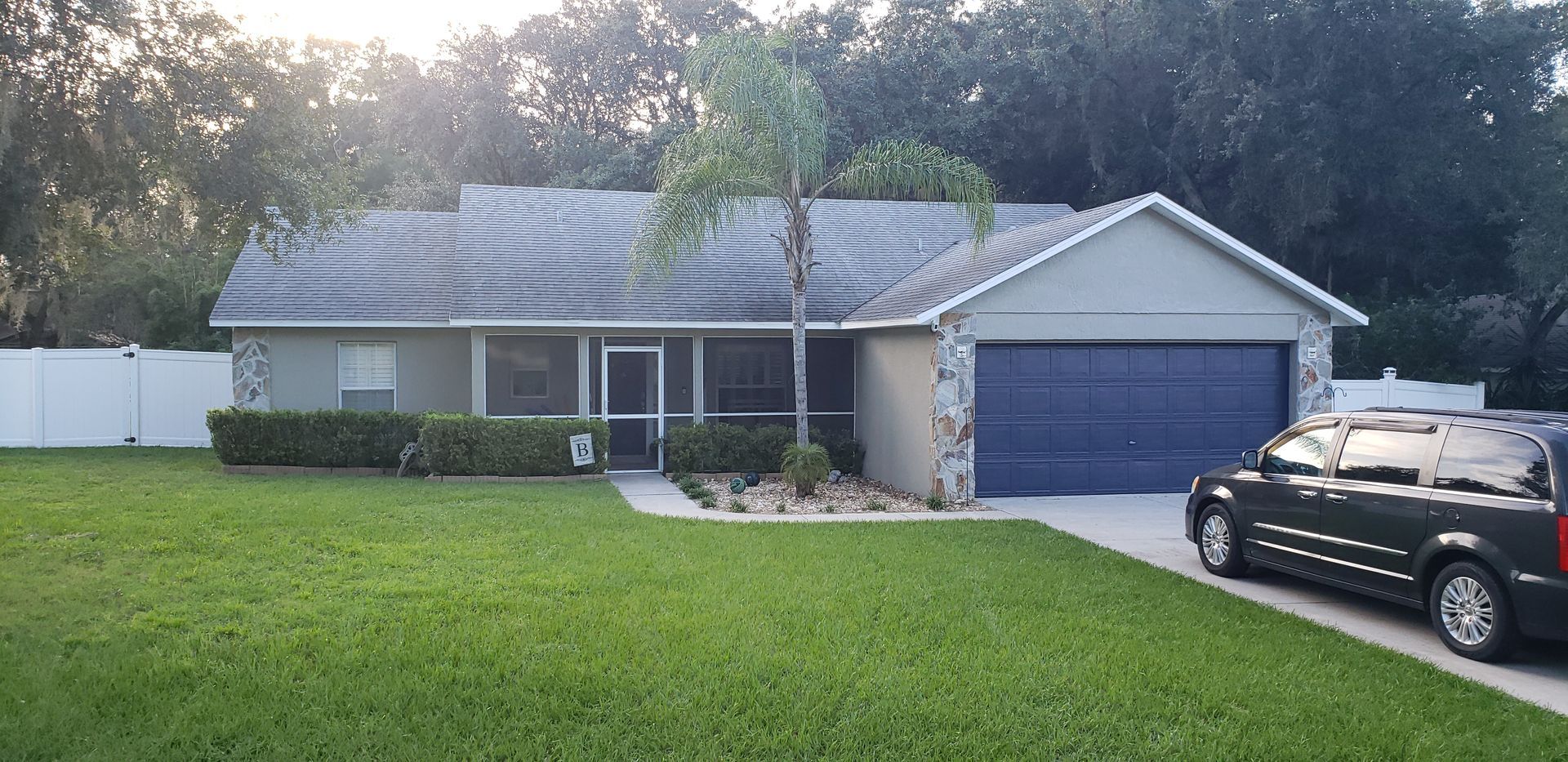 A black suv is parked in front of a house with a blue garage door.