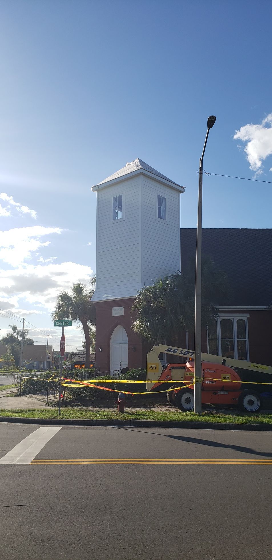 A large white tower is sitting on top of a red brick building next to a street.