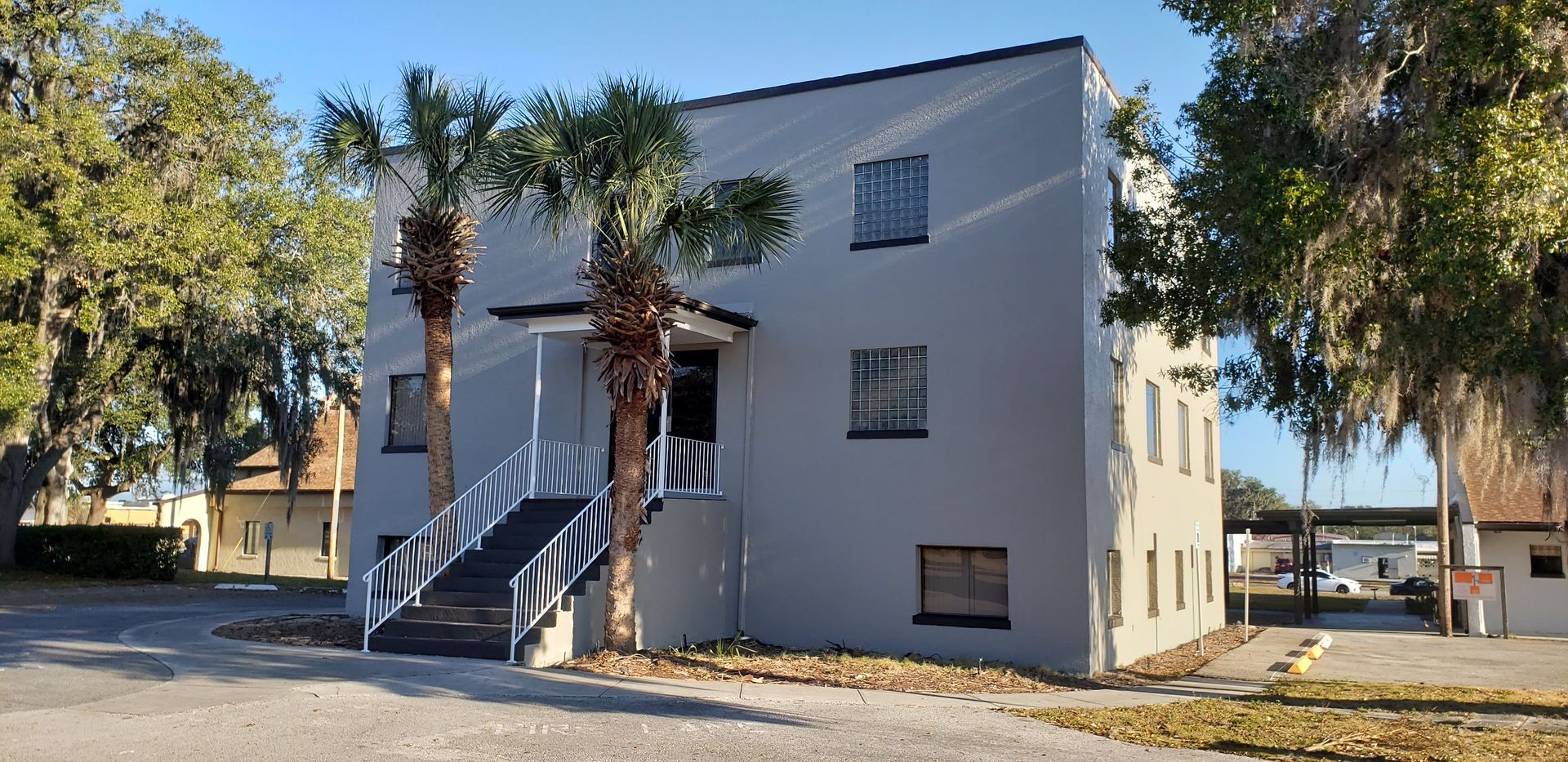 A white building with palm trees in front of it.