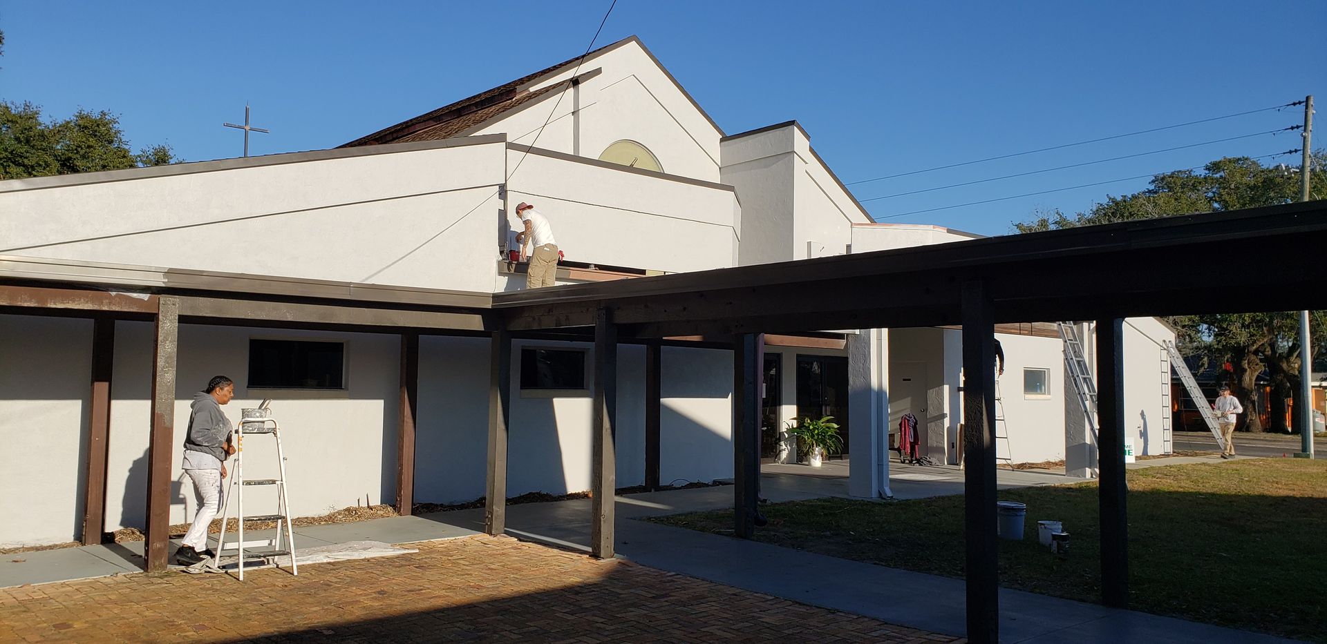 A man is standing on a ladder in front of a white building