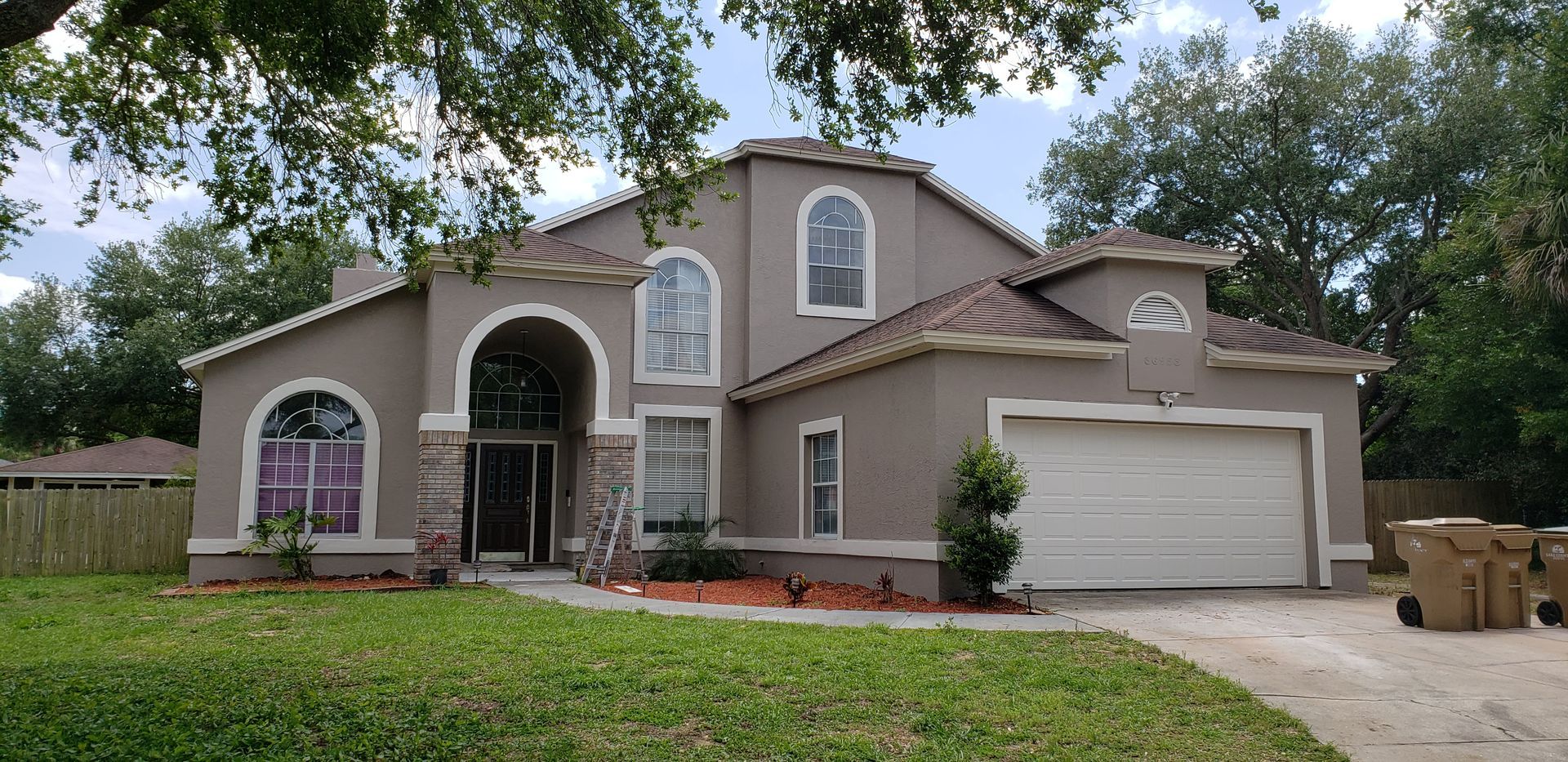 A large house with a white garage door is sitting on top of a lush green lawn.