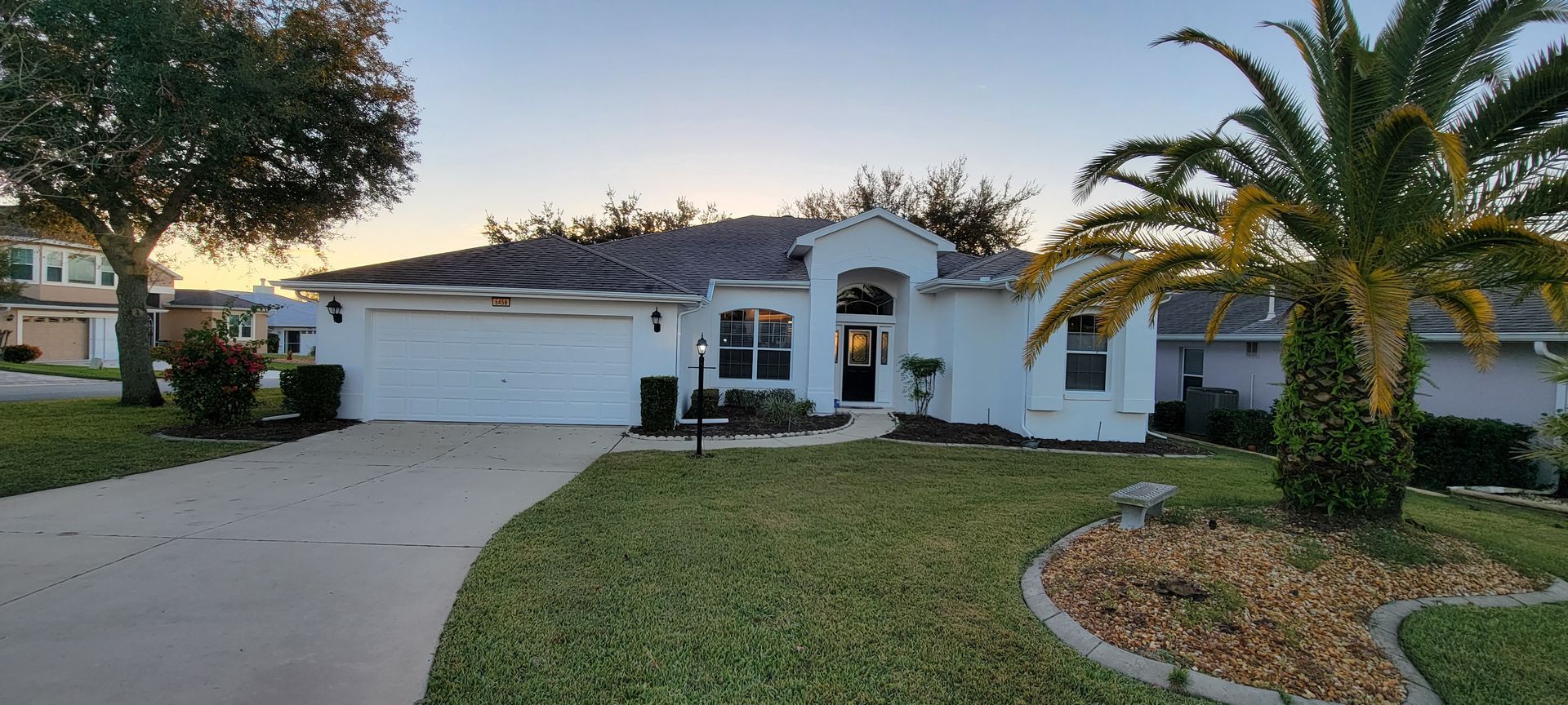 A white house with a palm tree in front of it.