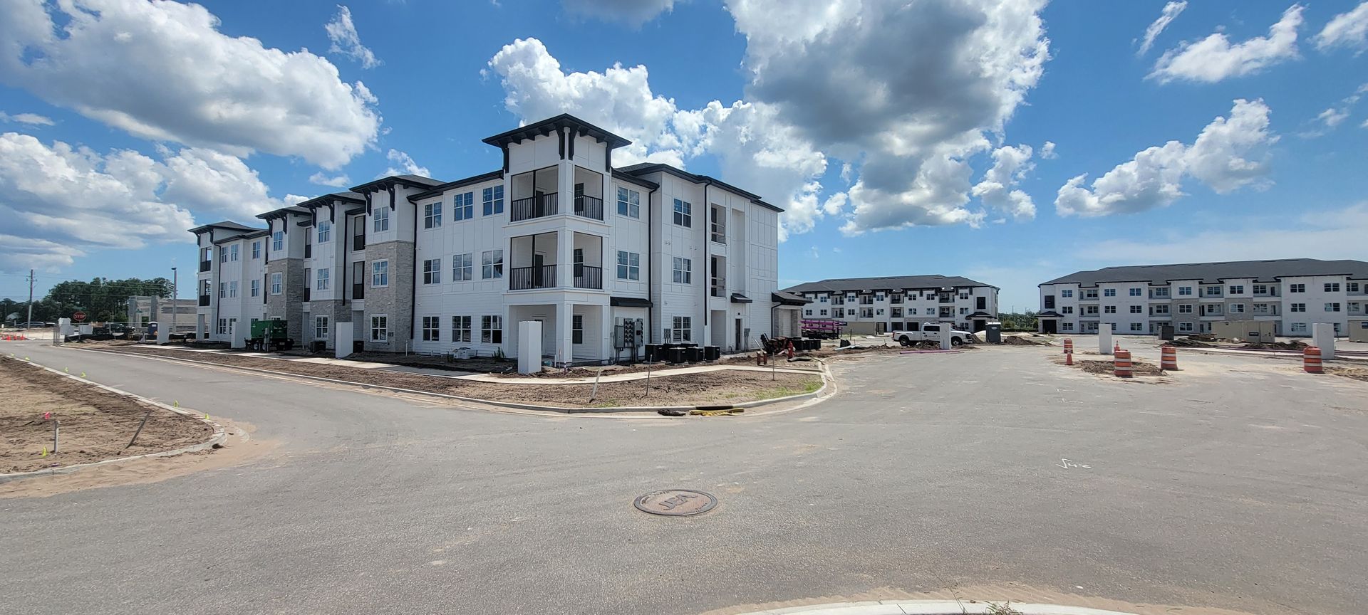 A large apartment building under construction with a lot of cars parked in front of it.