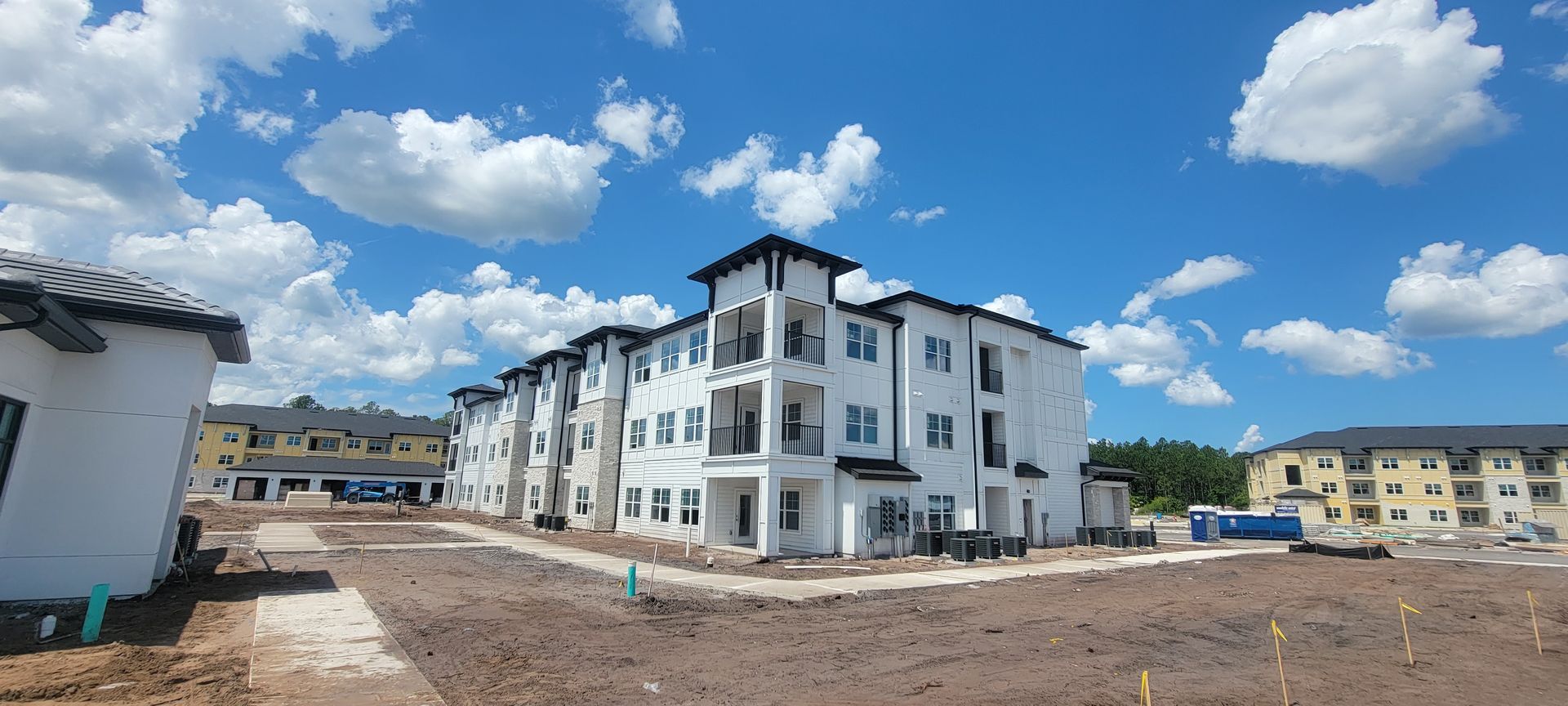 A large apartment building is being built in the middle of a dirt field.