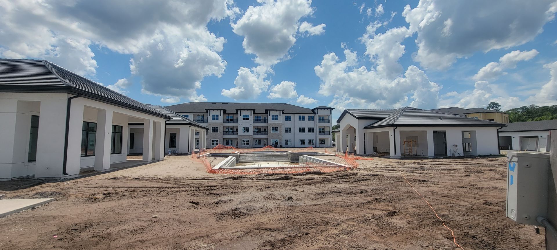 A large building is being built in the middle of a dirt field.