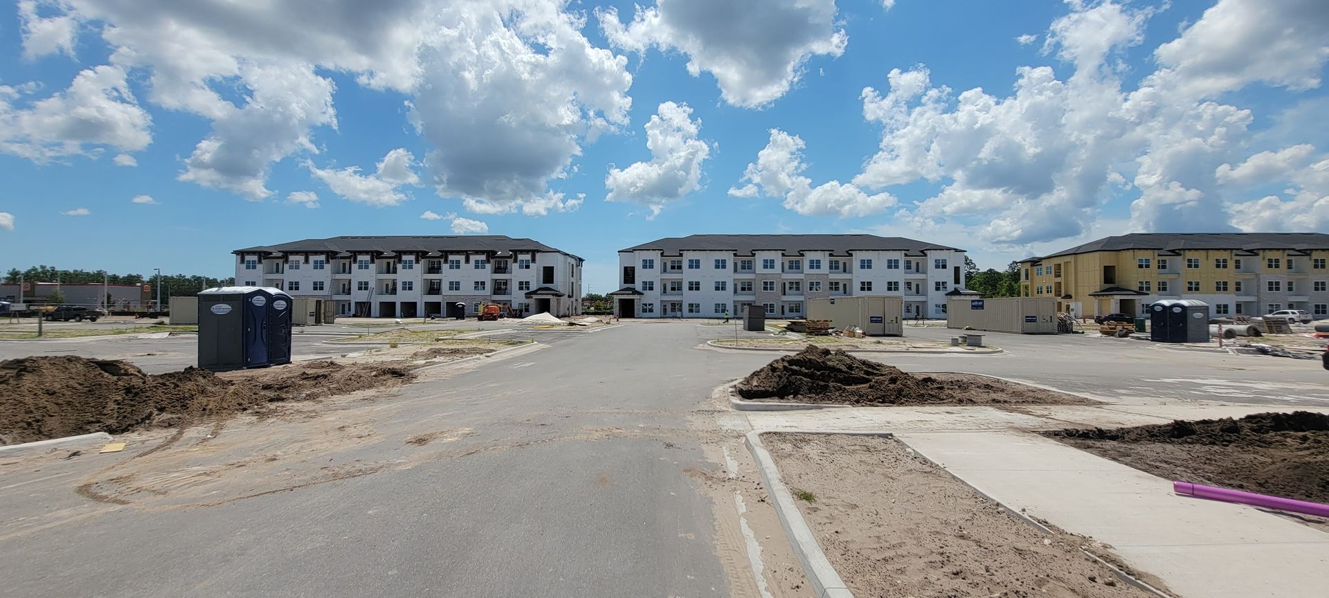 A row of buildings are being built on a dirt road.