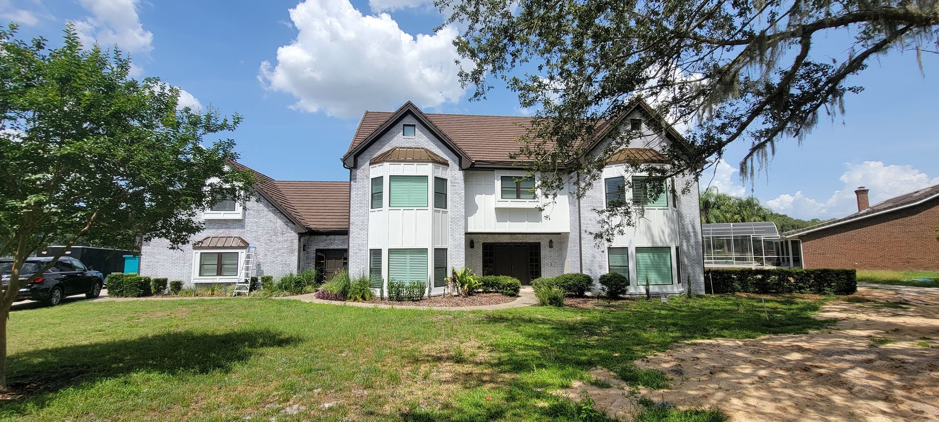 A large white house with a brown roof is sitting on top of a lush green lawn.