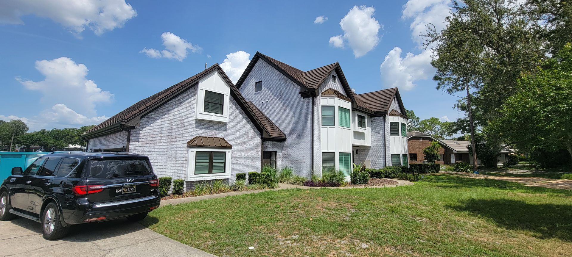 A large white house with a black suv parked in front of it.