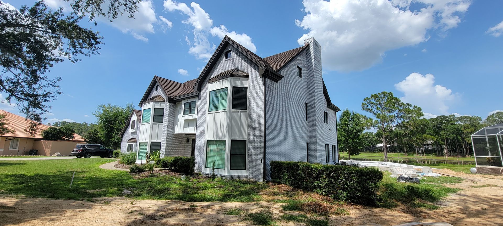 A large white house with a brown roof is sitting on top of a lush green field.