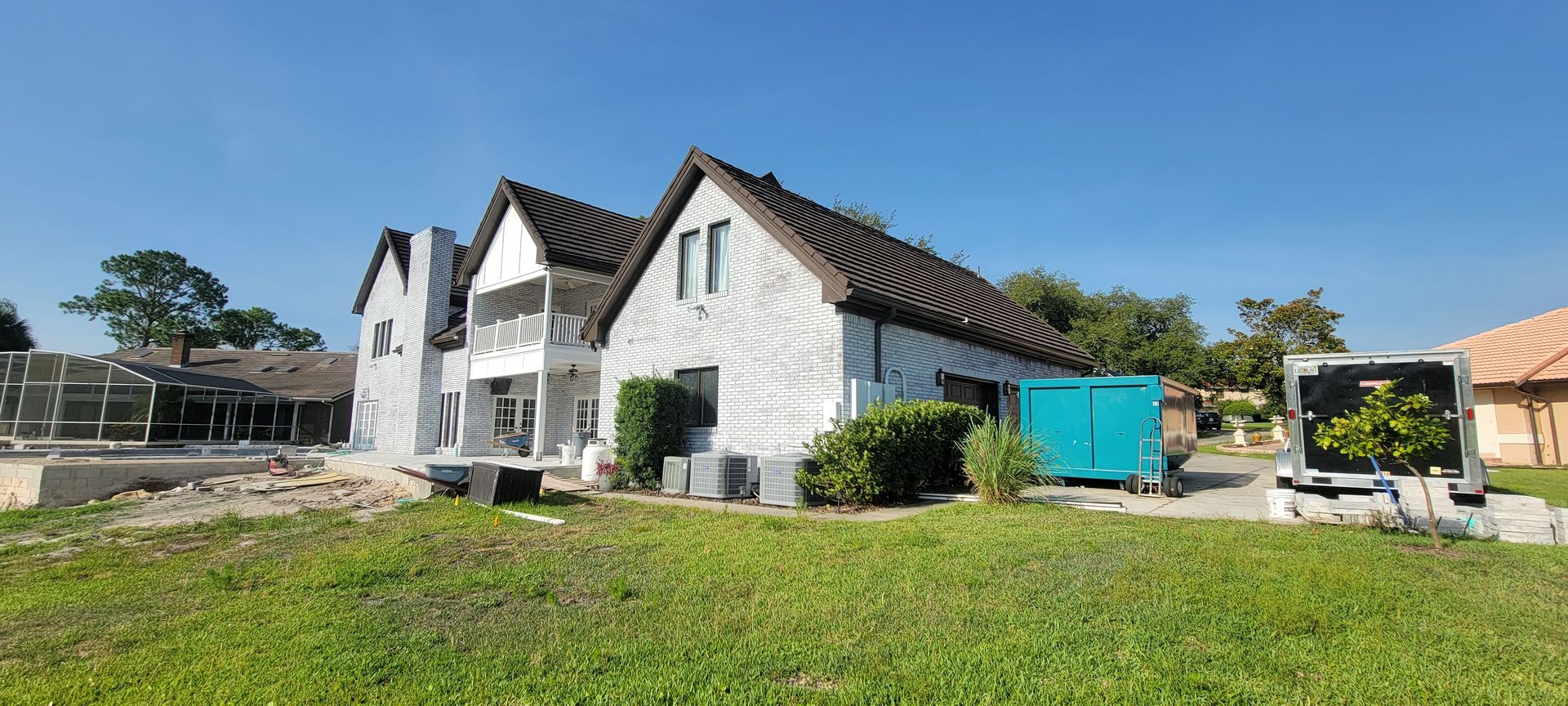A large white house is being built in the middle of a grassy field.