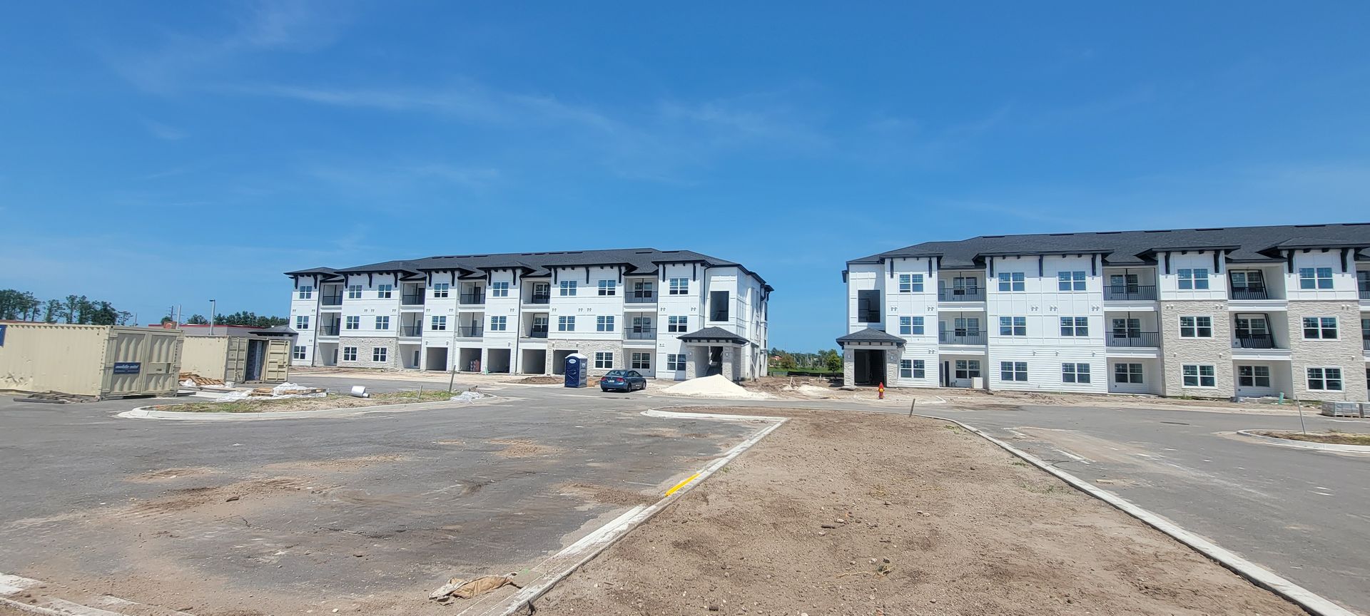 A large apartment building under construction with a parking lot in front of it.