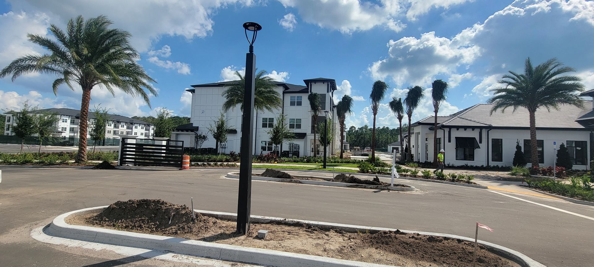 A parking lot with palm trees and a building in the background.
