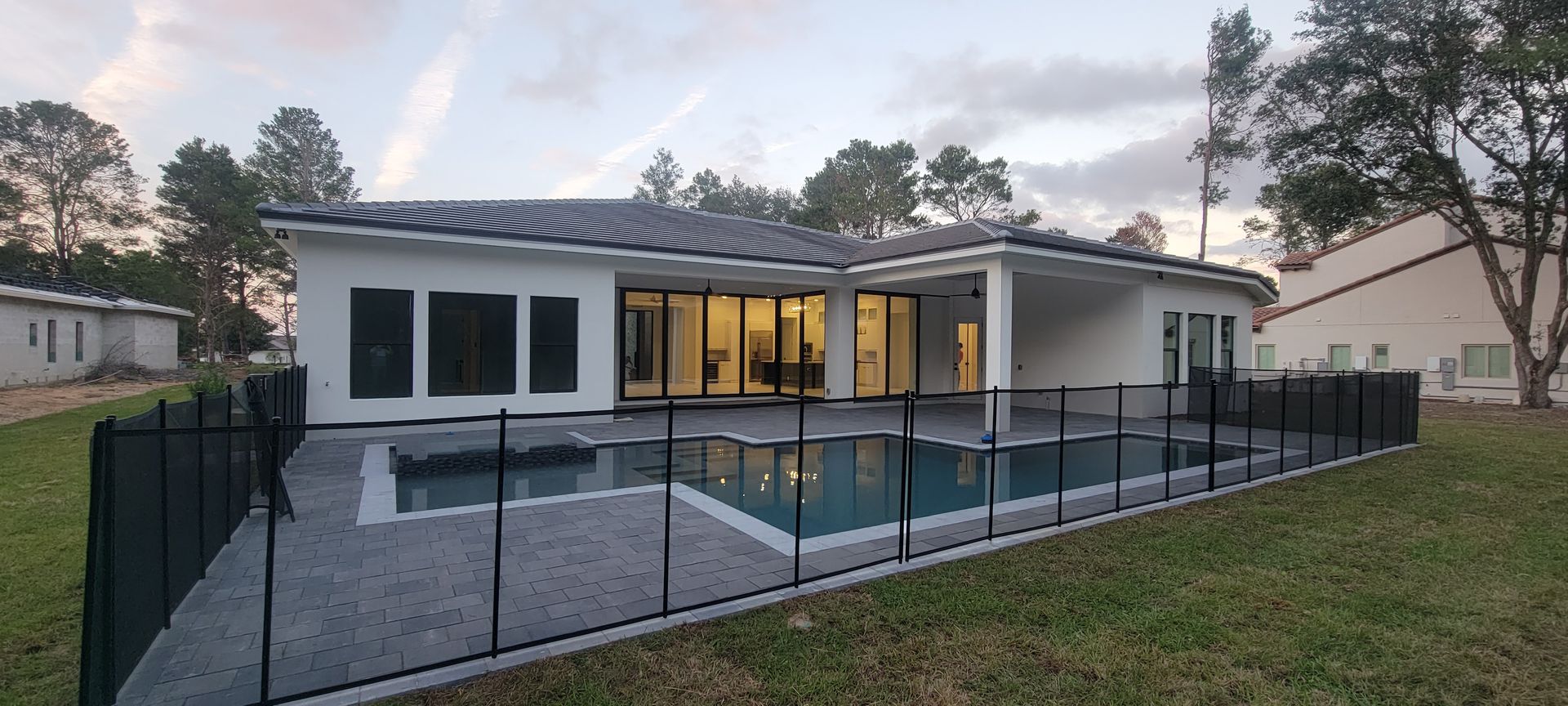 The back of a house with a fence around it and a swimming pool.
