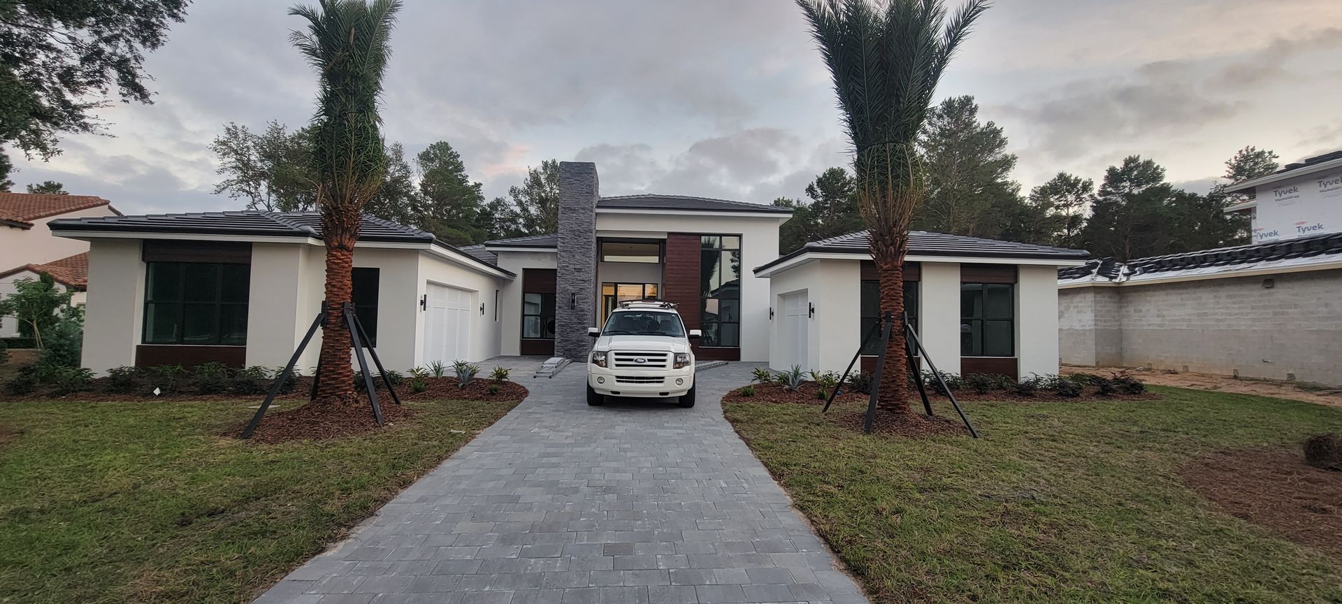 A white suv is parked in front of a white house.