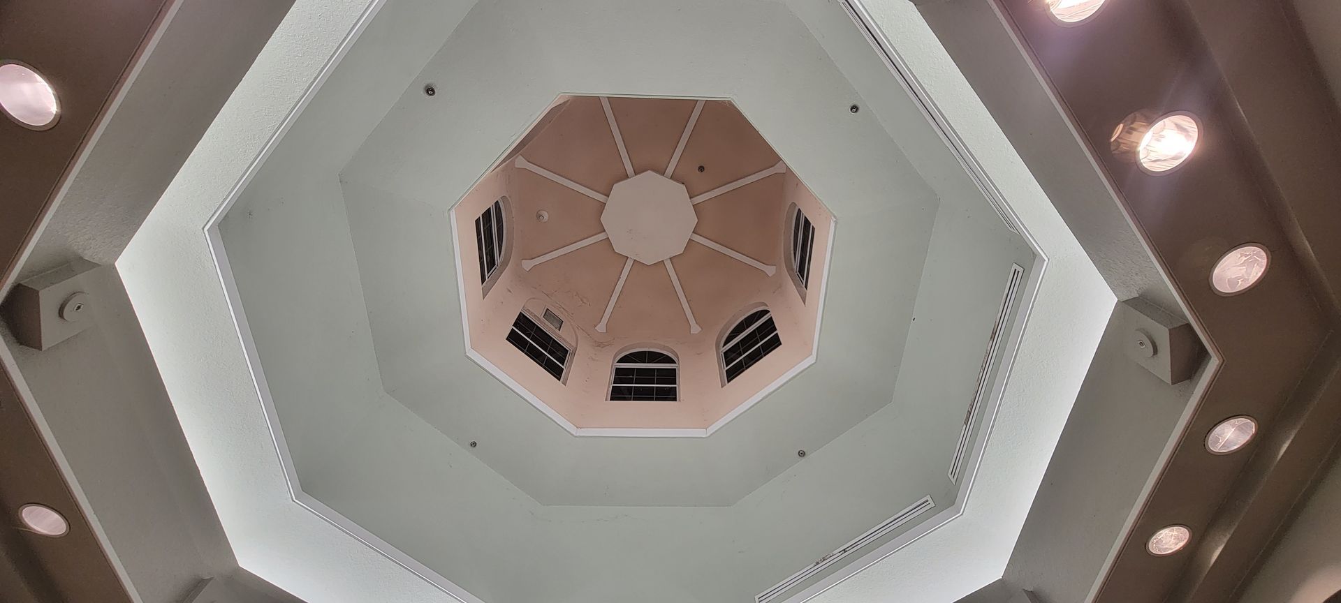 Looking up at the ceiling of a building with a dome in the middle.