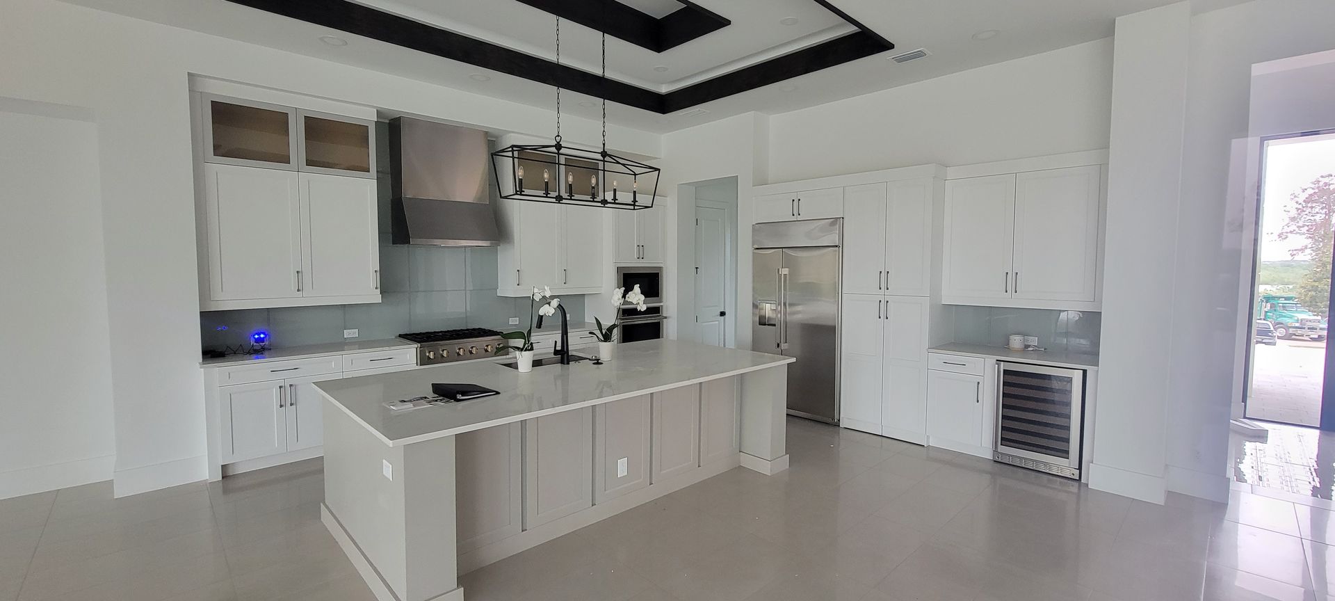 A kitchen with white cabinets , stainless steel appliances , and a large island.