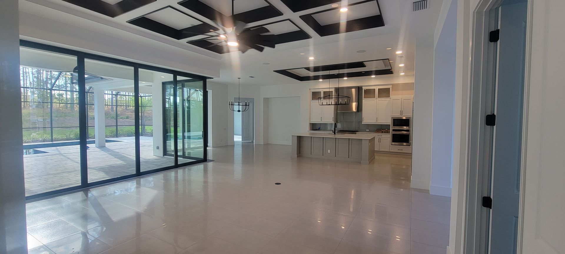 A large empty room with a lot of windows and a kitchen.