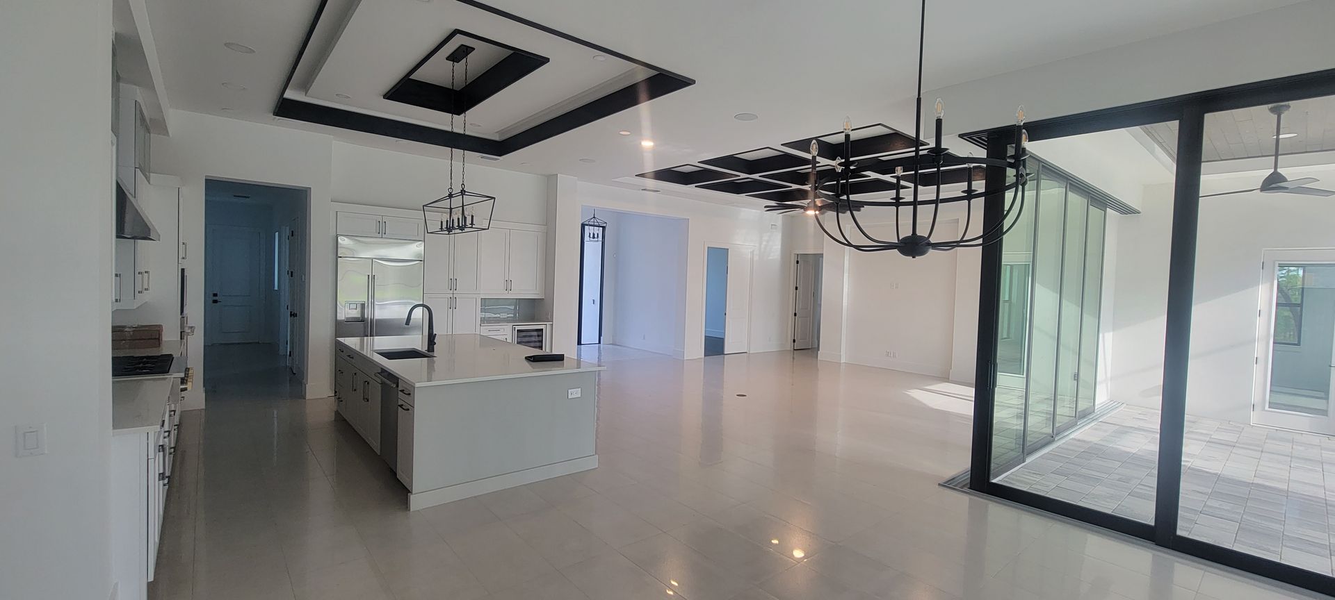 A large empty room with a kitchen and sliding glass doors.