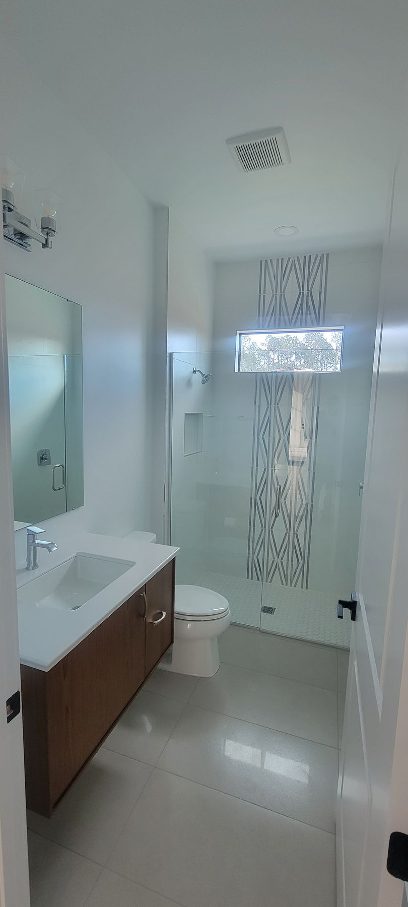 A bathroom with a sink , toilet , shower and mirror.