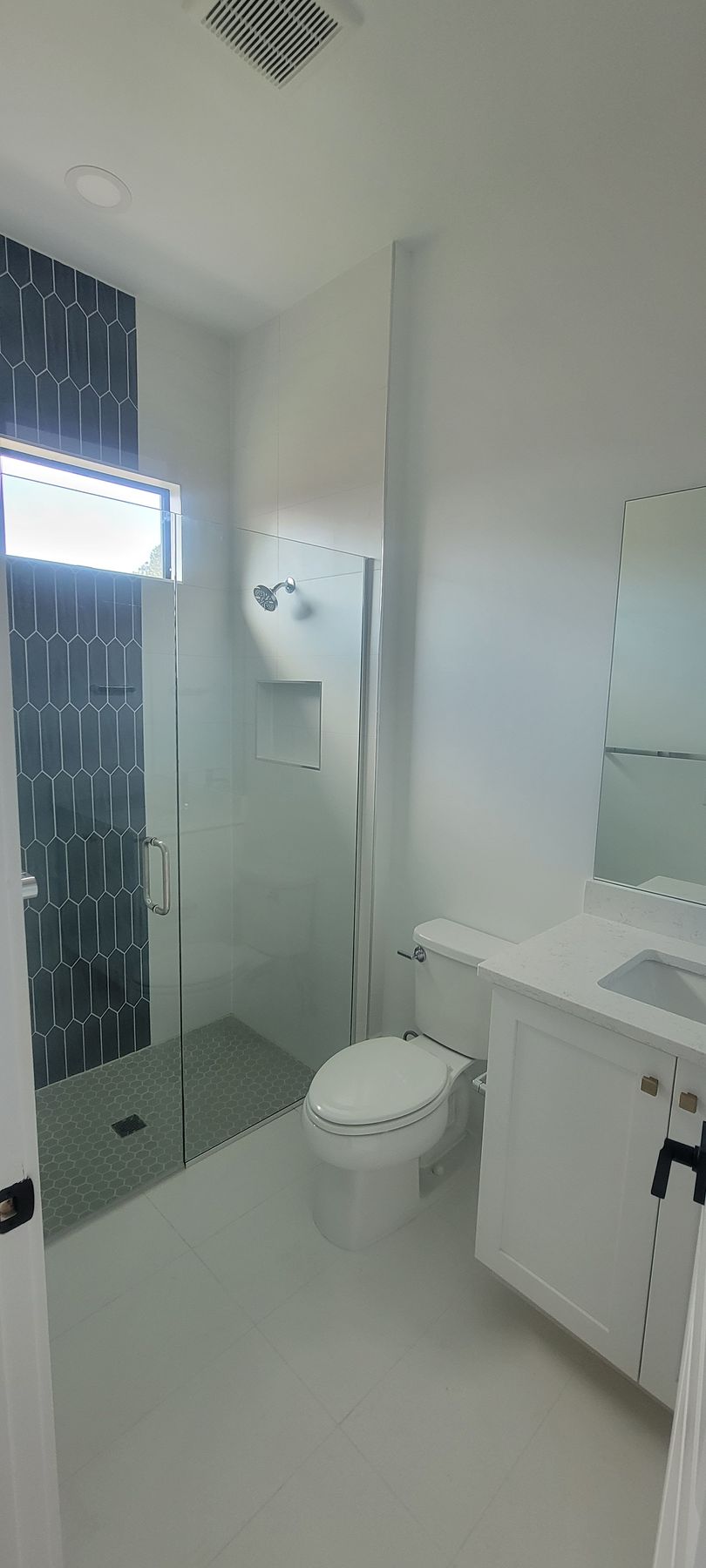 A bathroom with a toilet , sink , shower and mirror.