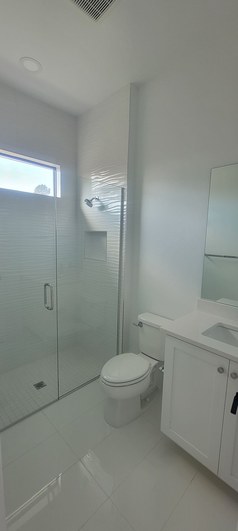 A bathroom with a toilet , sink , shower and mirror.