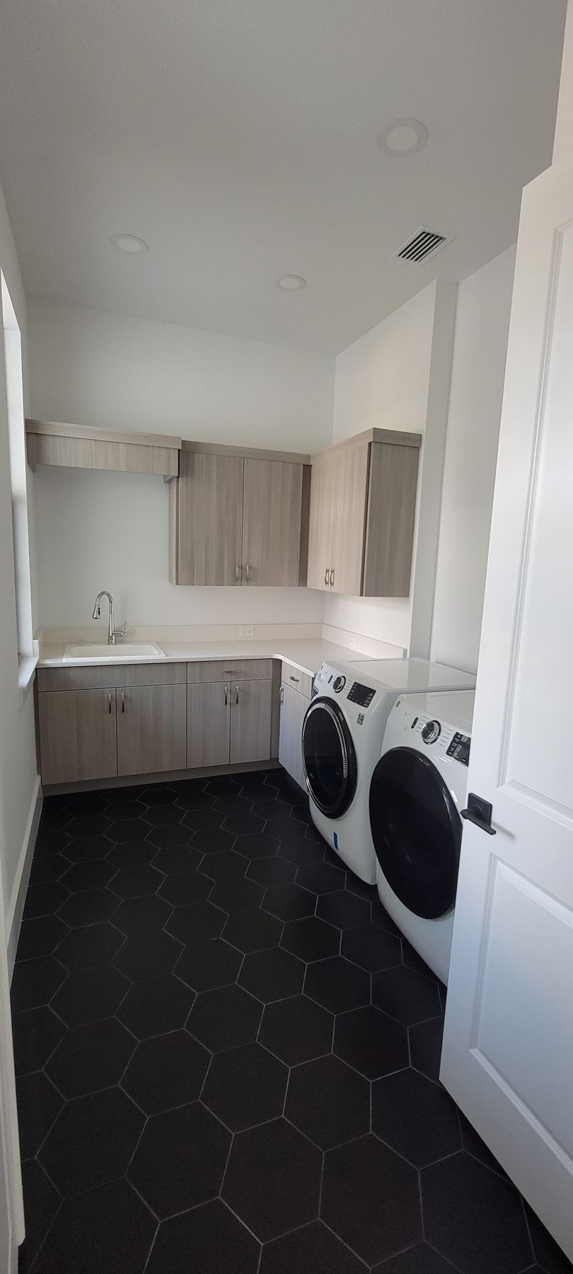 A laundry room with a washer and dryer and a sink.